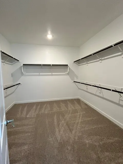 Spacious walk-in closet featuring white walls, recessed lighting, and expansive shelving with integrated hanging rods