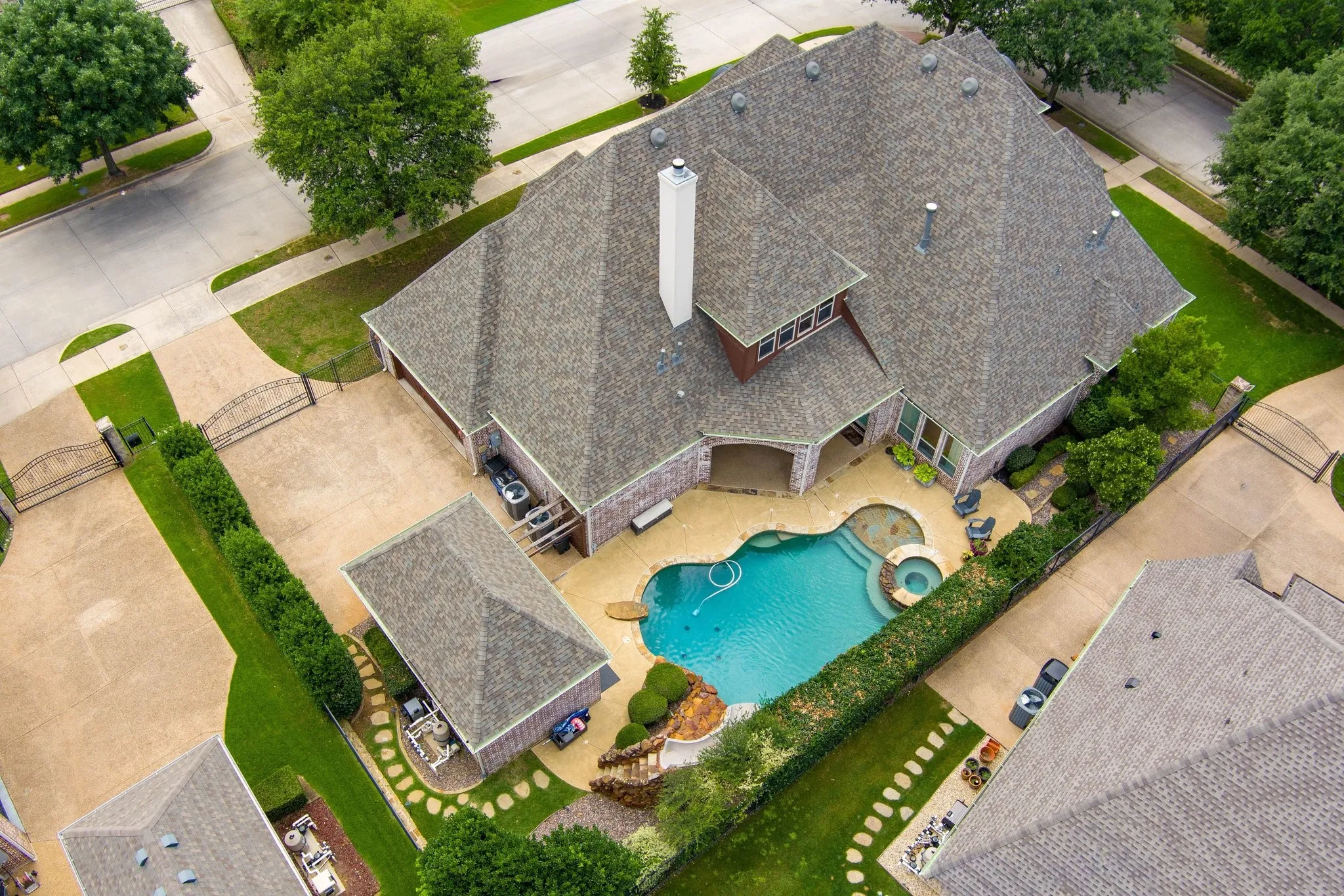 Expansive property featuring a multi-gabled roofline and an integrated swimming pool with a spa