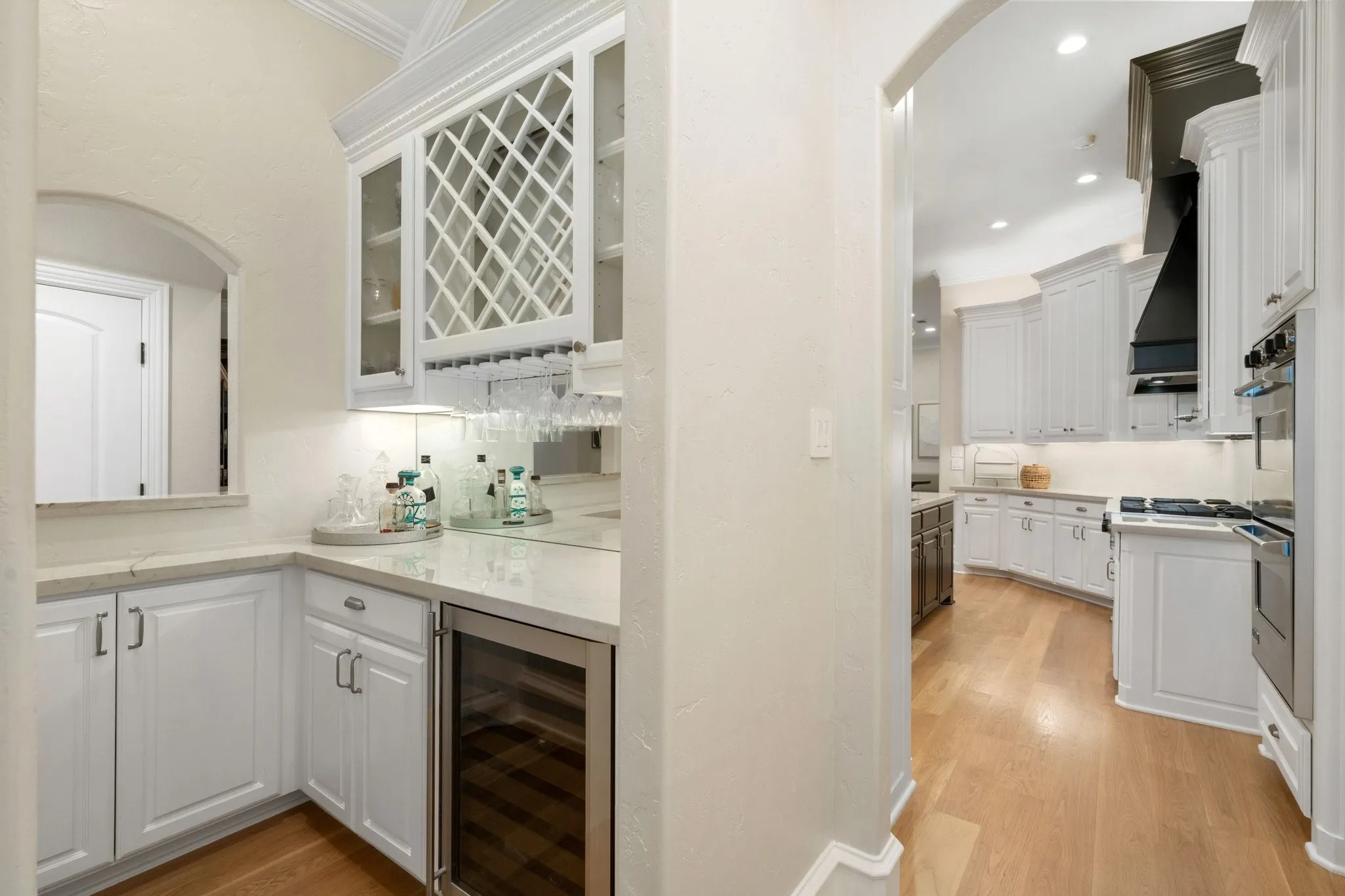 Built-in wet bar featuring white cabinetry, a built-in wine rack, glass-front display cabinets, and a beverage cooler
