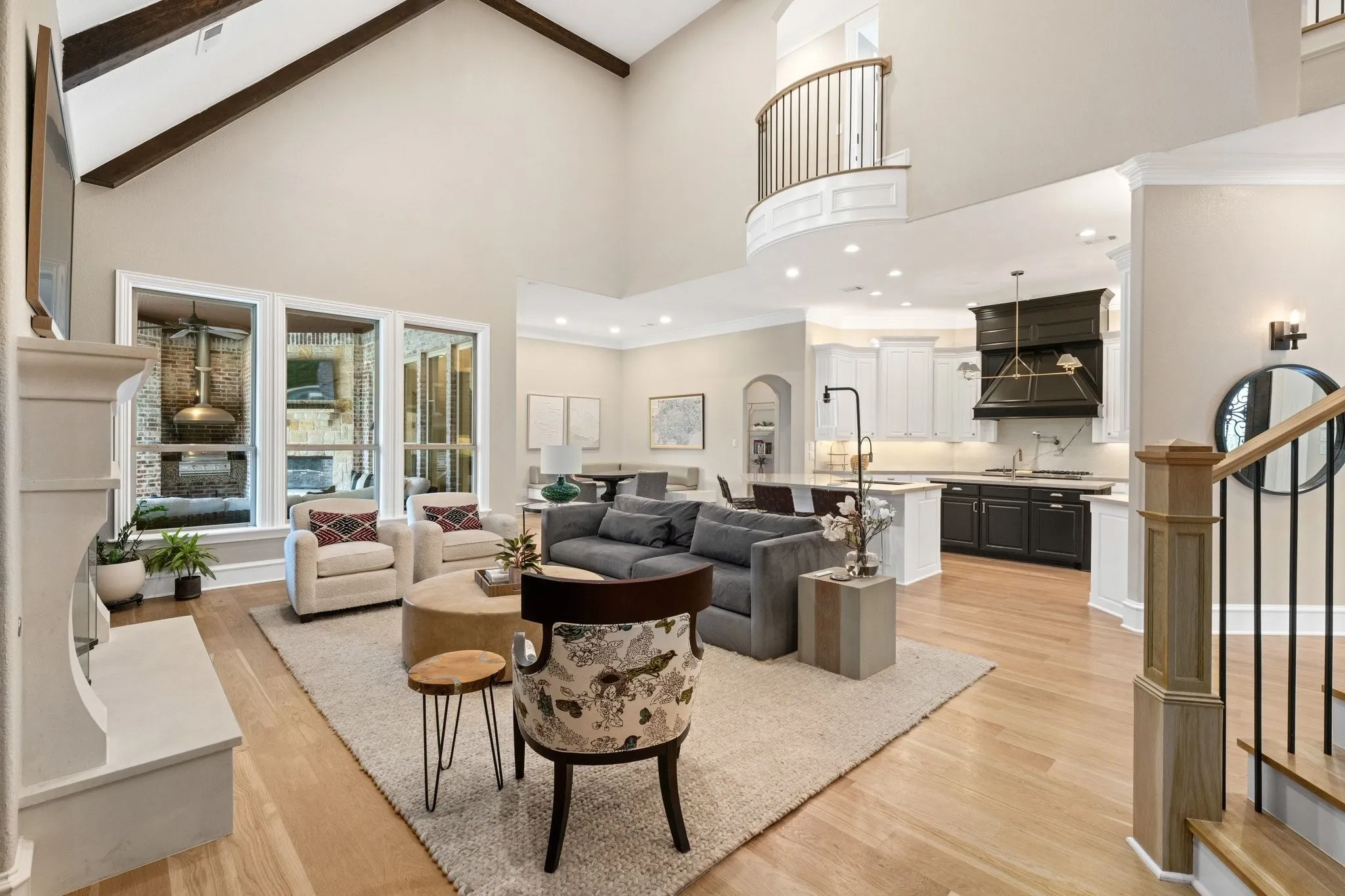 Vaulted ceiling living room featuring wood-finish flooring, a white mantel, and a wall of windows