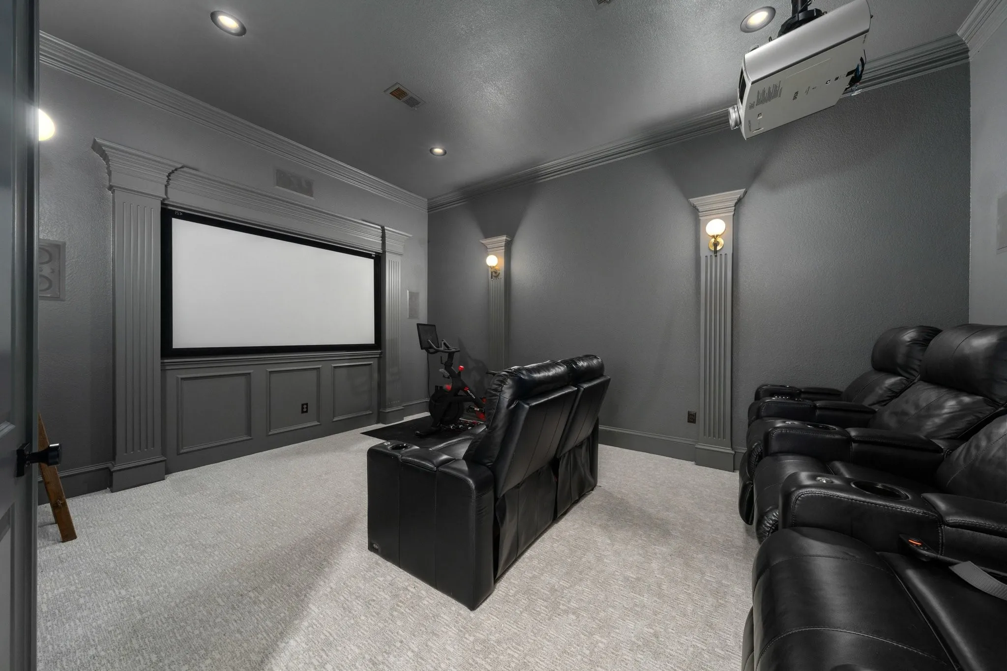 Dedicated media room featuring a large projection screen, recessed lighting, and wall sconces