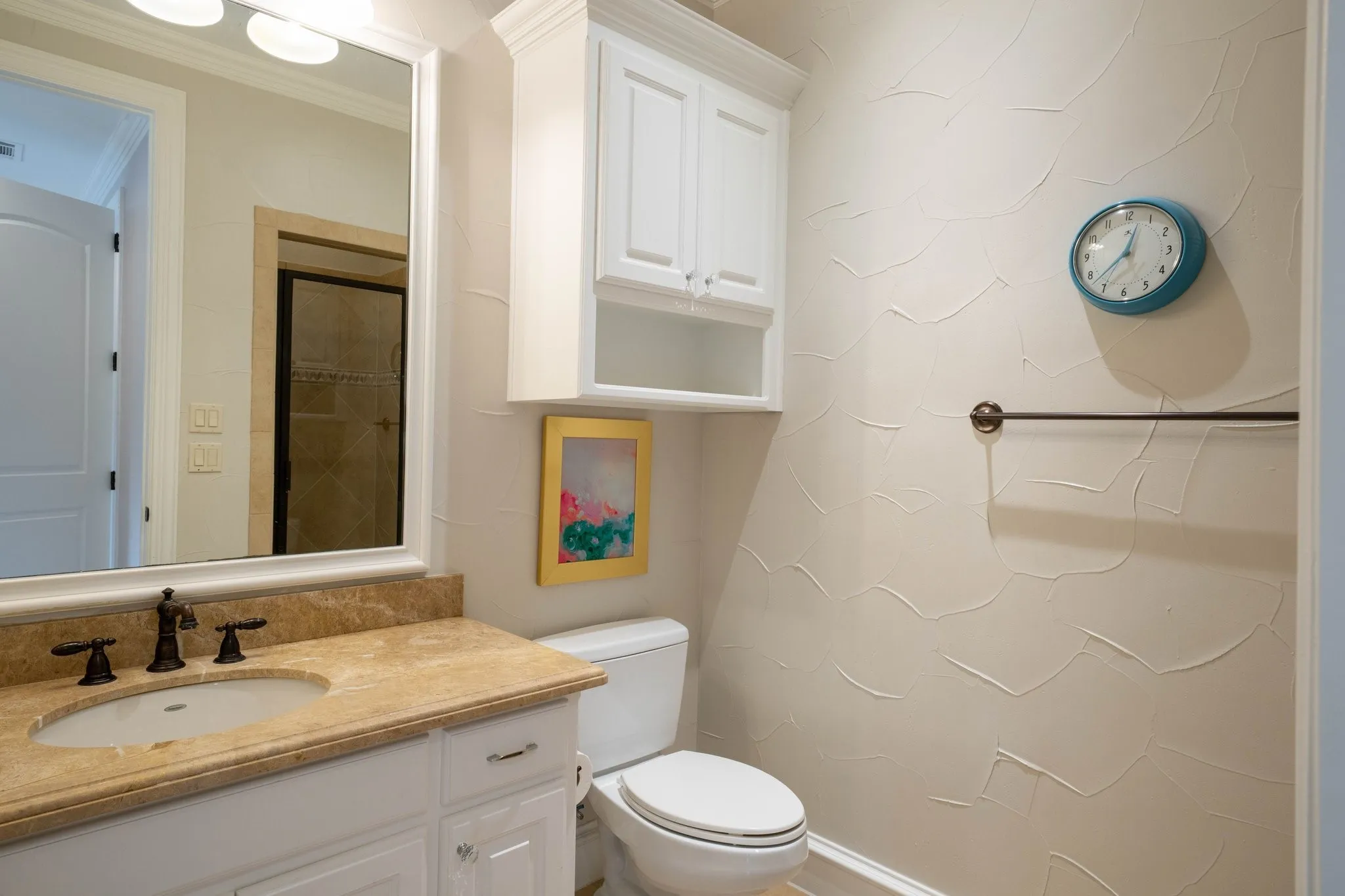 Bathroom featuring a single vanity with a stone countertop, an undermount sink, and dark bronze-finish fixtures