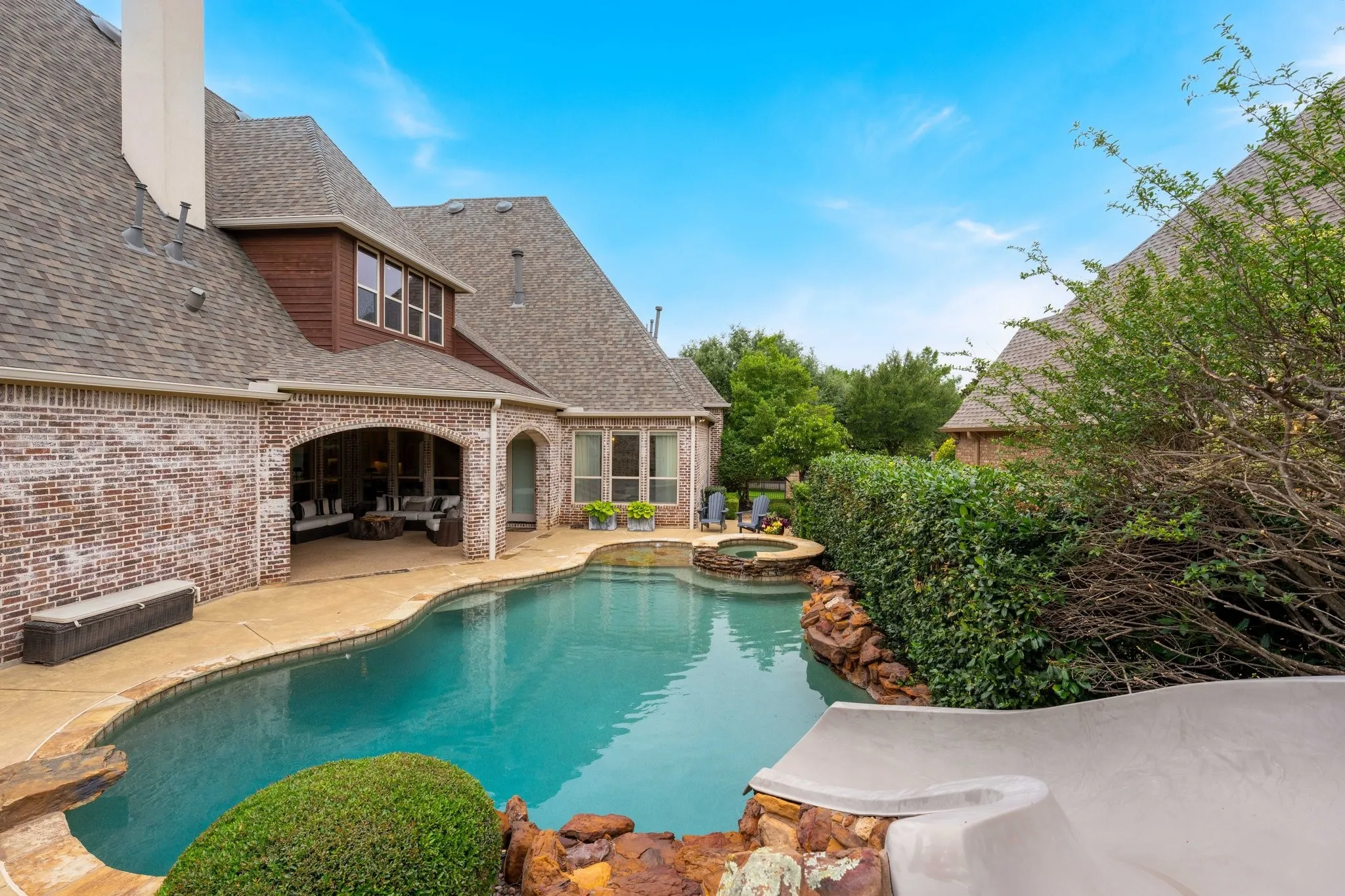 Expansive backyard featuring a custom-shaped swimming pool, integrated spa, and a built-in water slide
