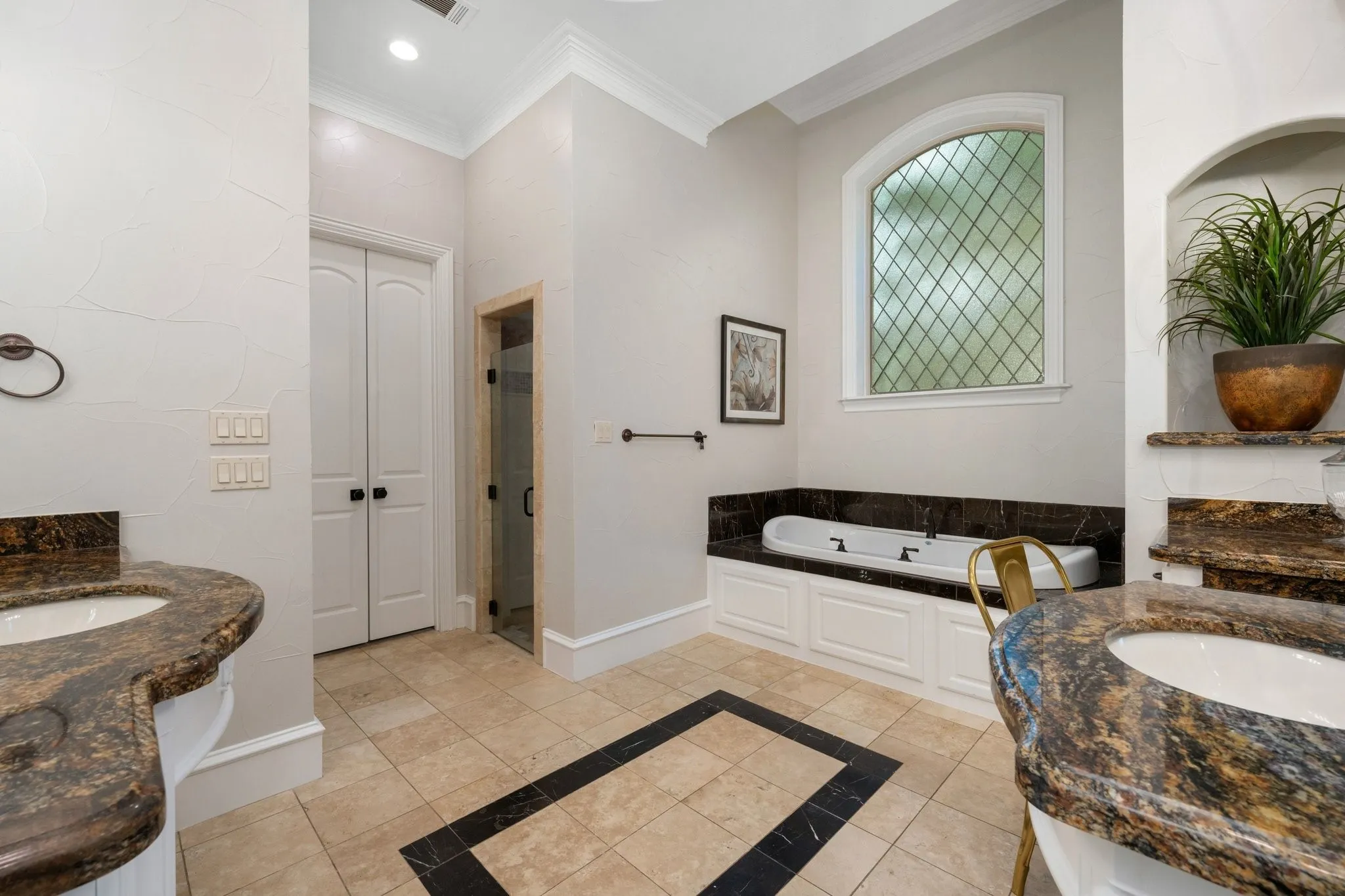 Recessed bathtub featuring a decorative leaded glass window and a dark stone surround