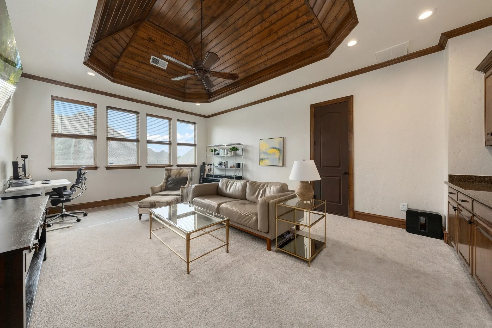 Spacious room featuring a wood-paneled tray ceiling with ceiling fan, recessed lighting, and crown molding