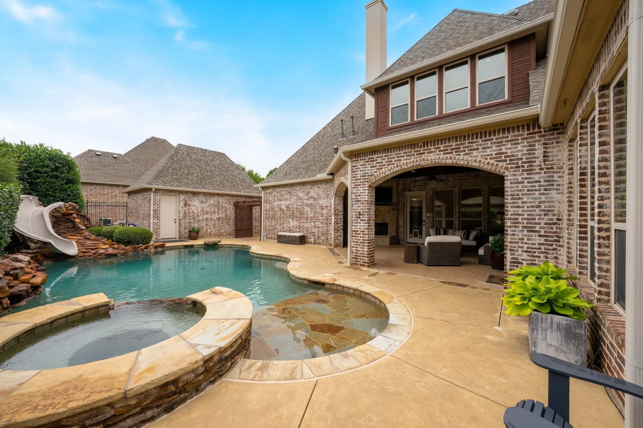 Backyard oasis featuring a freeform swimming pool with integrated spa and rock waterfall slide