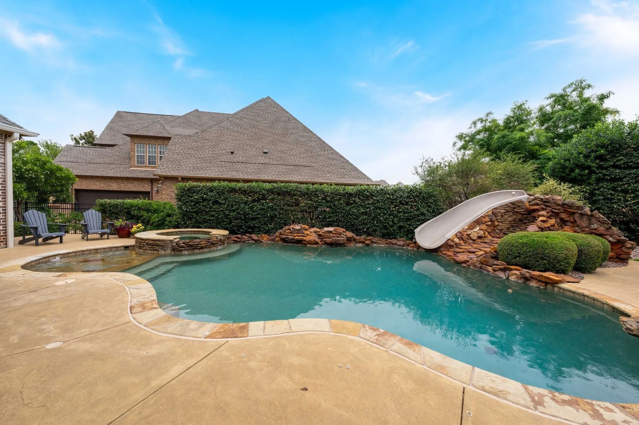 Expansive pool area featuring a freeform swimming pool, integrated spa, and rock waterfall slide feature