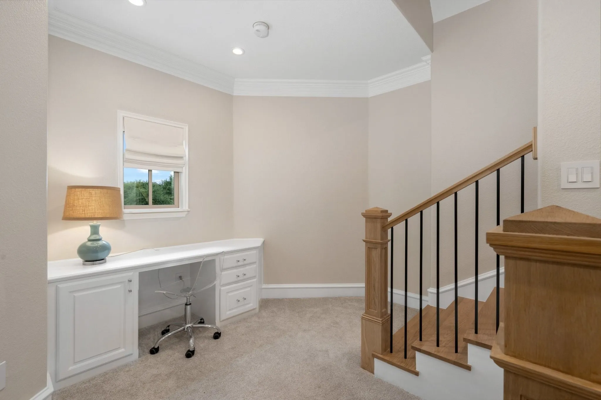 Built-in desk featuring white cabinetry, a window with natural light, recessed lighting, crown molding, and neutral-toned carpeting