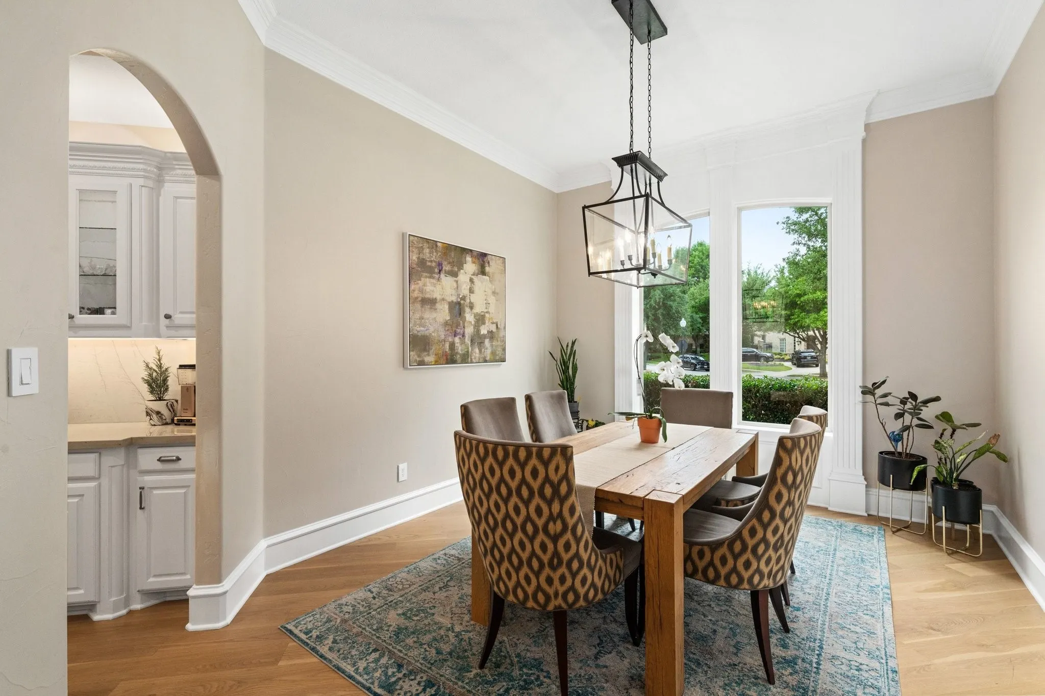 Dining area featuring wood-finish flooring, a contemporary chandelier, crown molding, and large windows with decorative trim