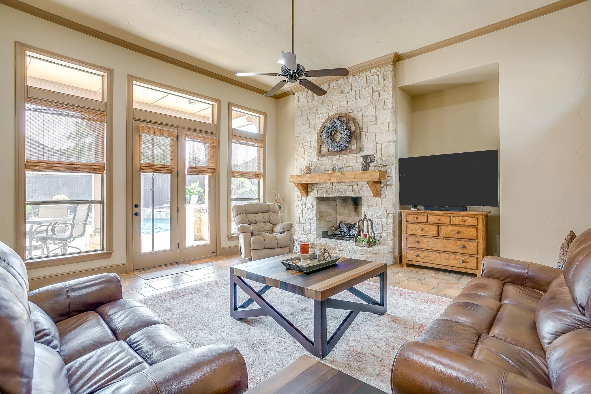 Living area featuring a stone fireplace with a wood mantle, vaulted ceiling with a ceiling fan, and tile flooring