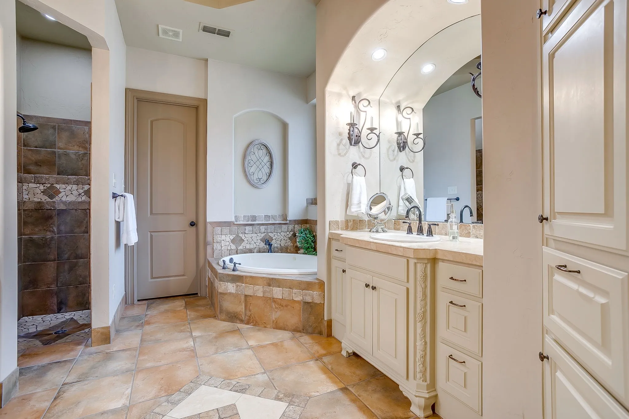 Bathroom featuring a corner soaking tub, a separate tiled shower, and a vanity with a countertop and dual wall sconces