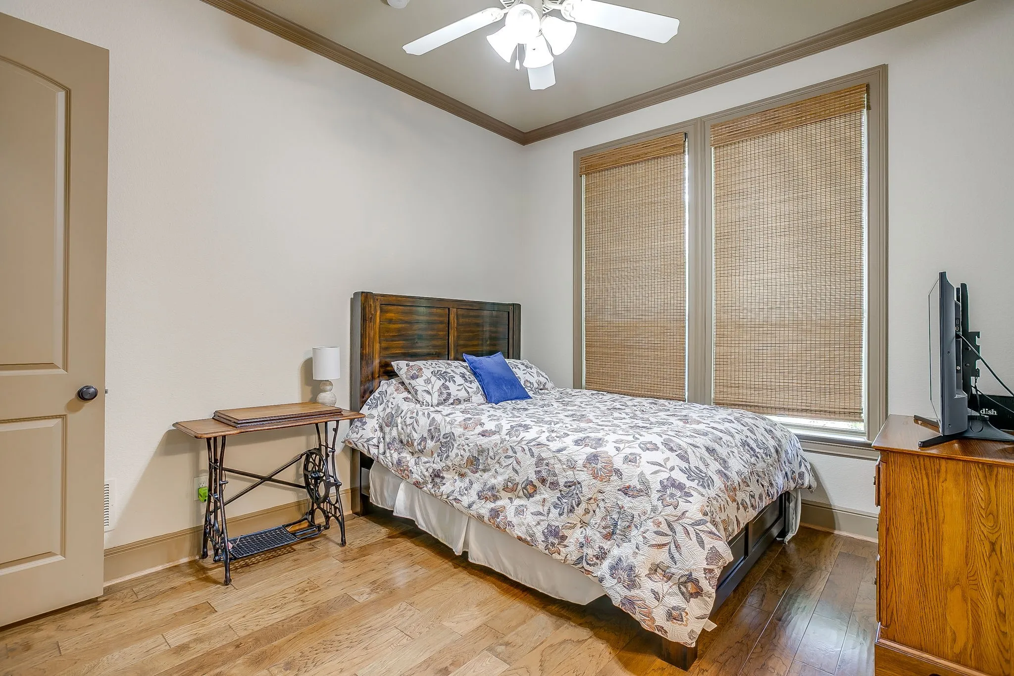 Bedroom #4 with Hardwood-style flooring throughout the room features a ceiling fan, crown molding, and two windows with woven shades