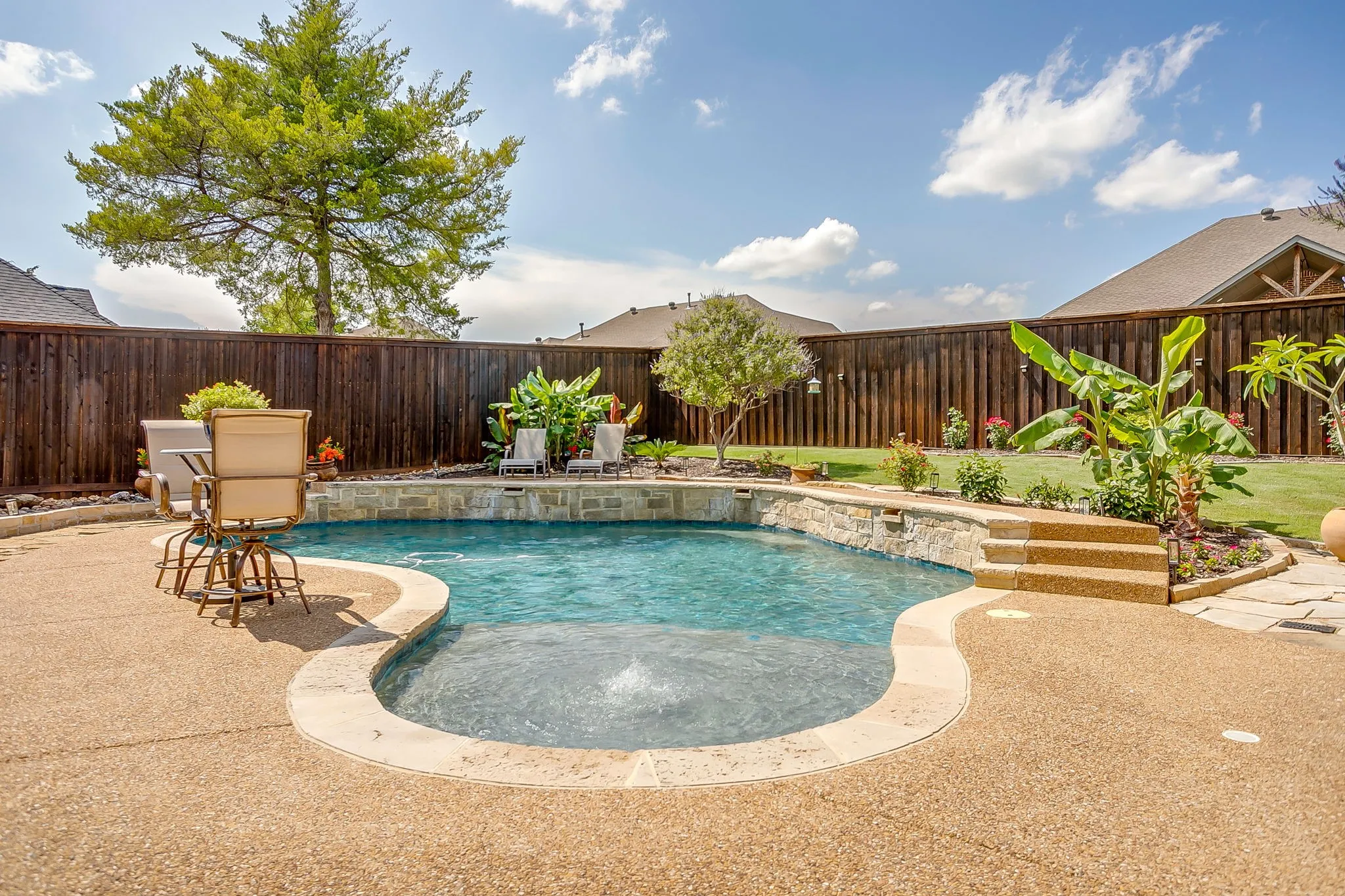 Kidney-shaped pool featuring stone coping and a waterfall feature