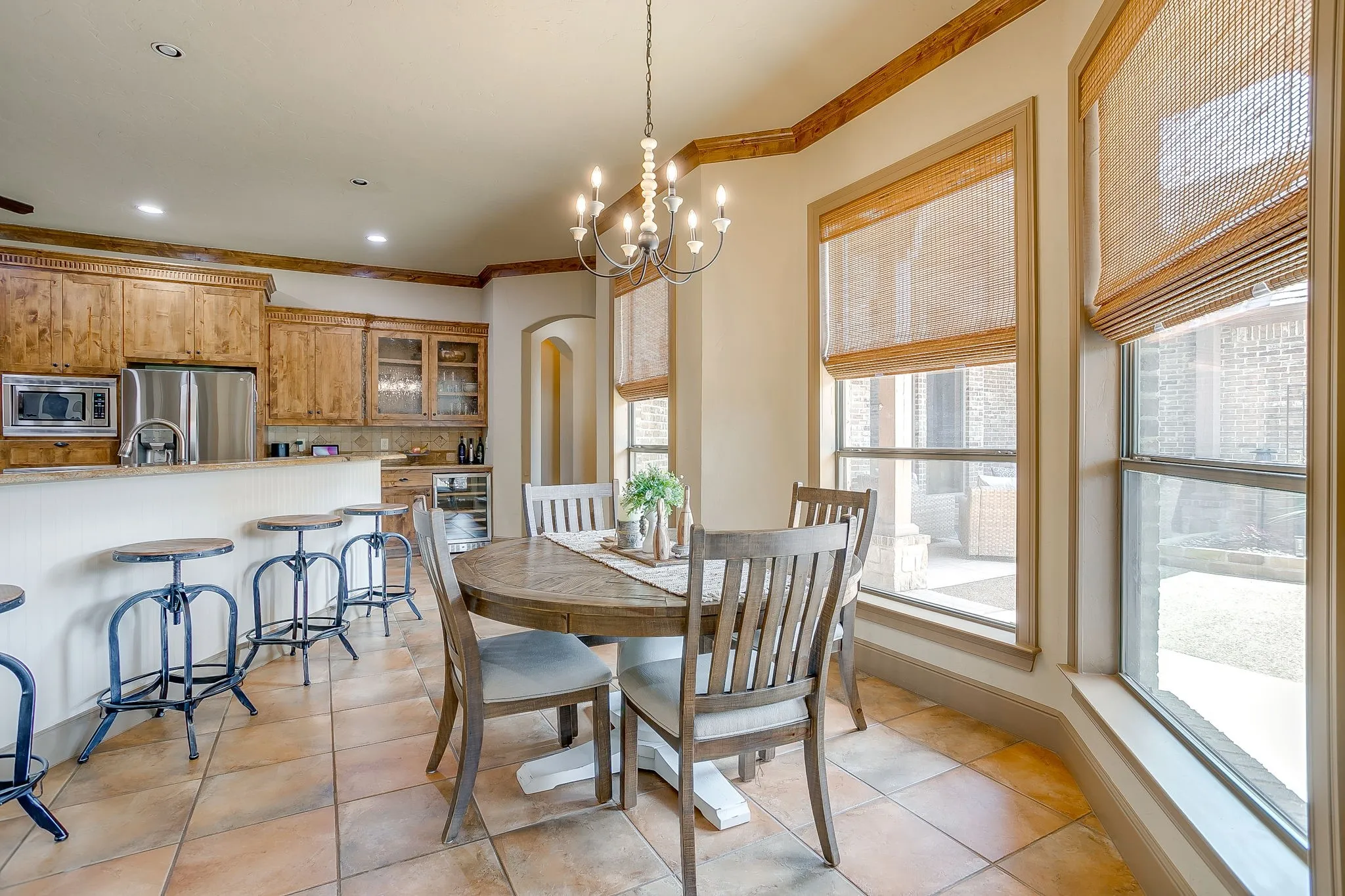 Kitchen and dining area featuring warm-toned wood cabinetry, stainless steel appliances, a built-in wine cooler, and tile flooring