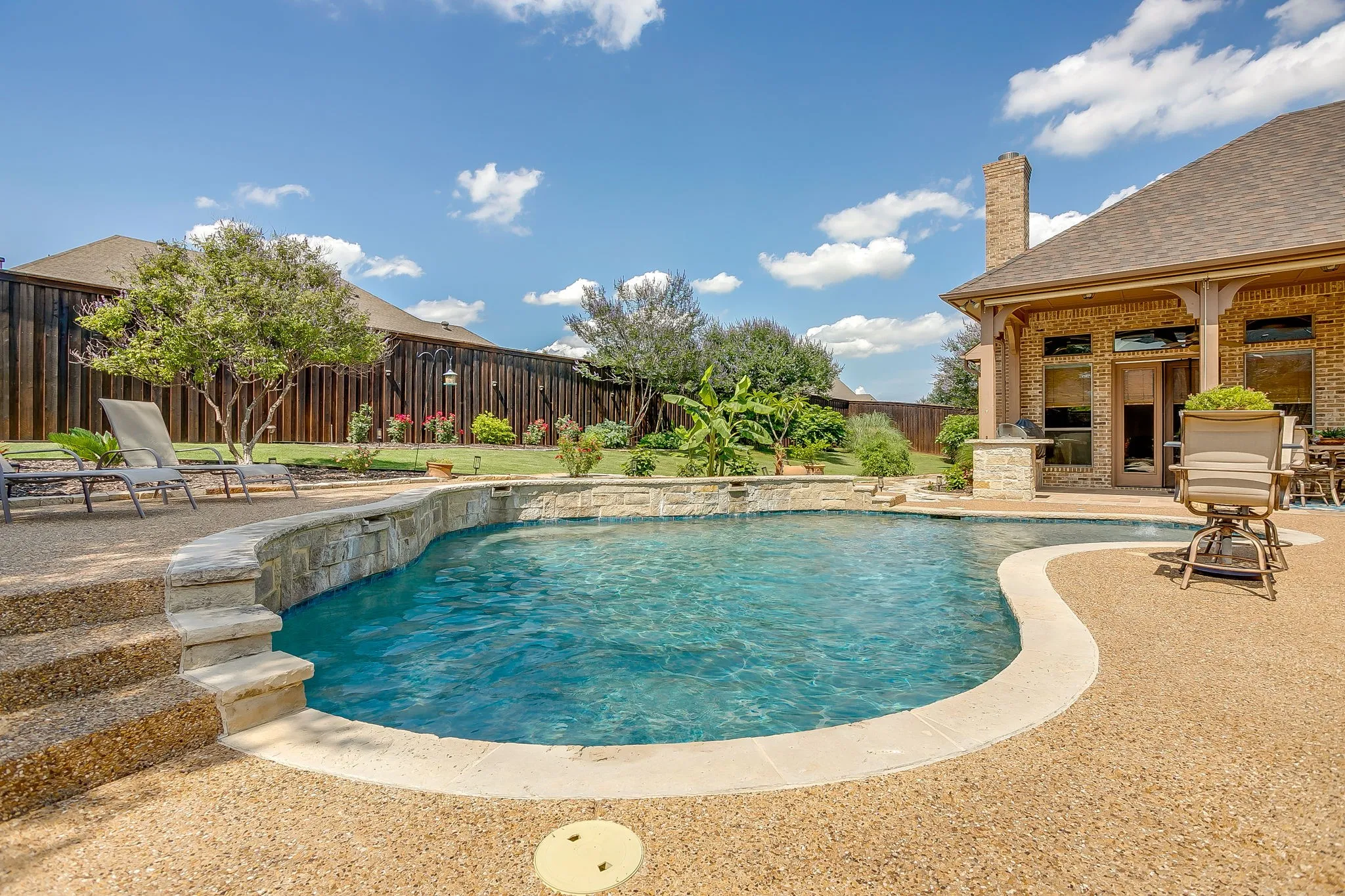 Curved swimming pool with stone coping and a raised stone spa