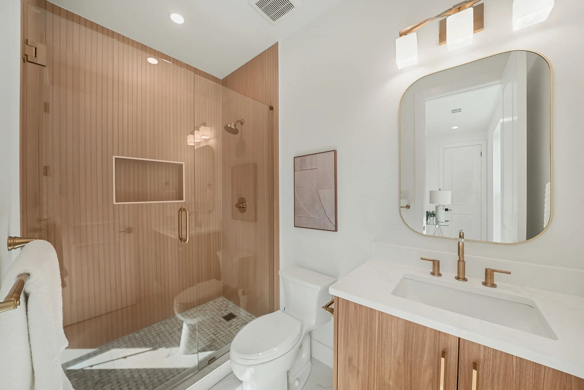 Bathroom featuring a glass-enclosed shower with fluted wood-finish wall panels and a built-in niche