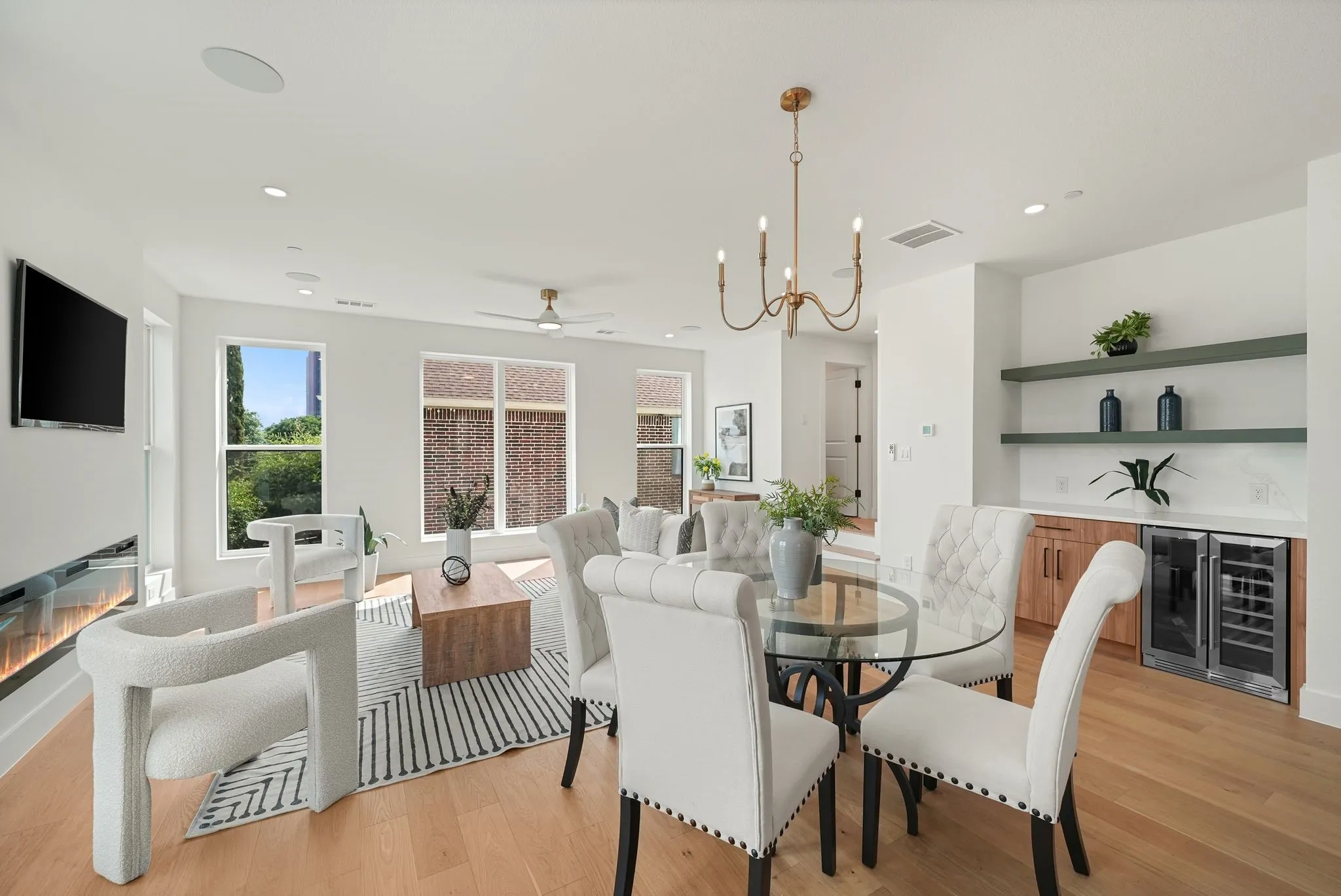 Open-concept living area featuring light wood-finish flooring, recessed lighting, and a modern linear fireplace