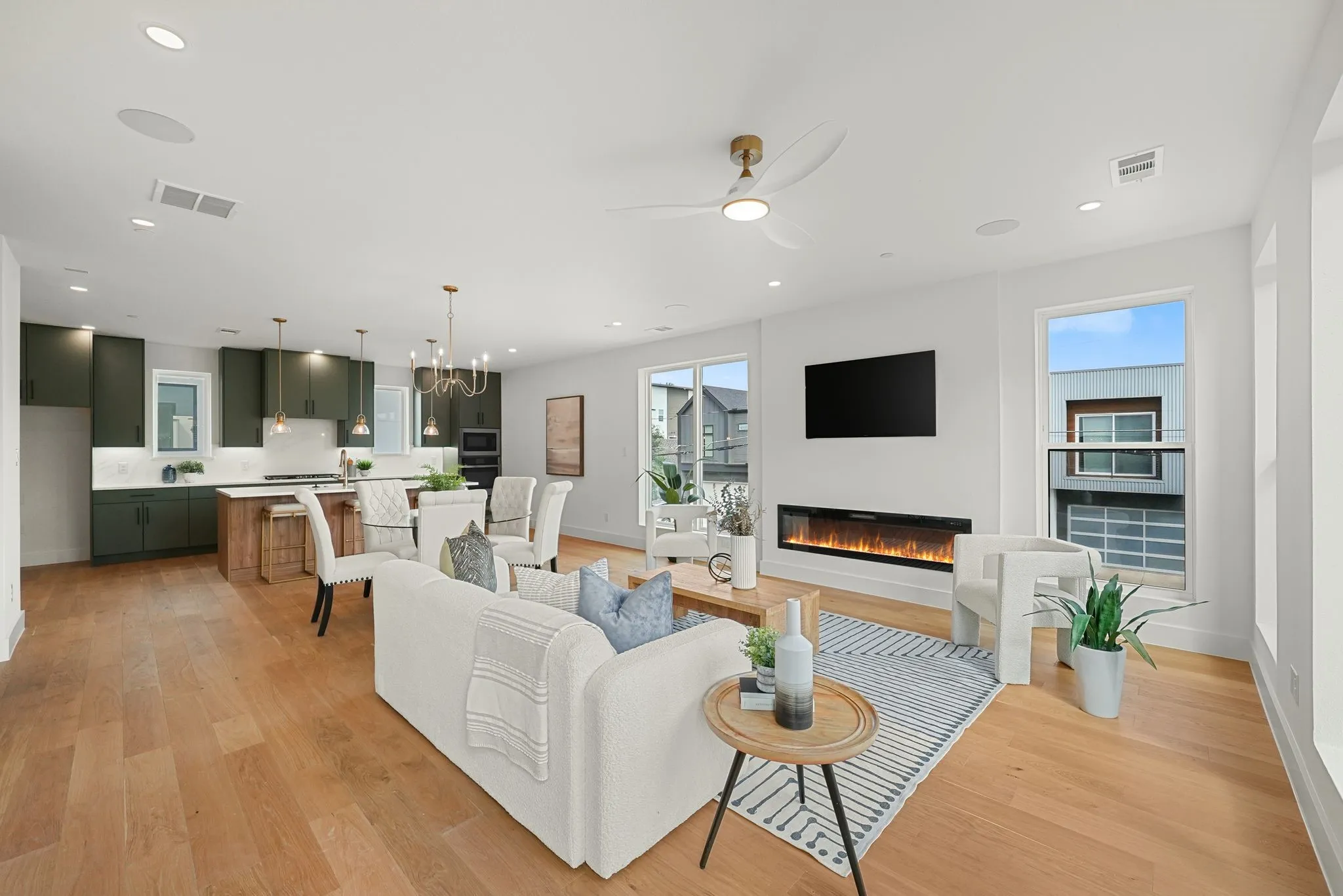 Open-concept interior featuring wood-finish flooring, recessed lighting, and a linear electric fireplace