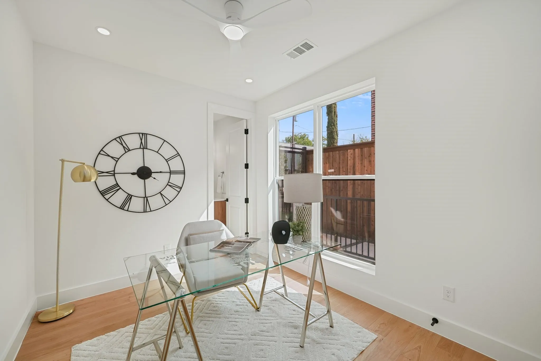 Bright room featuring light wood-finish flooring, white walls, a multi-pane window, and recessed lighting