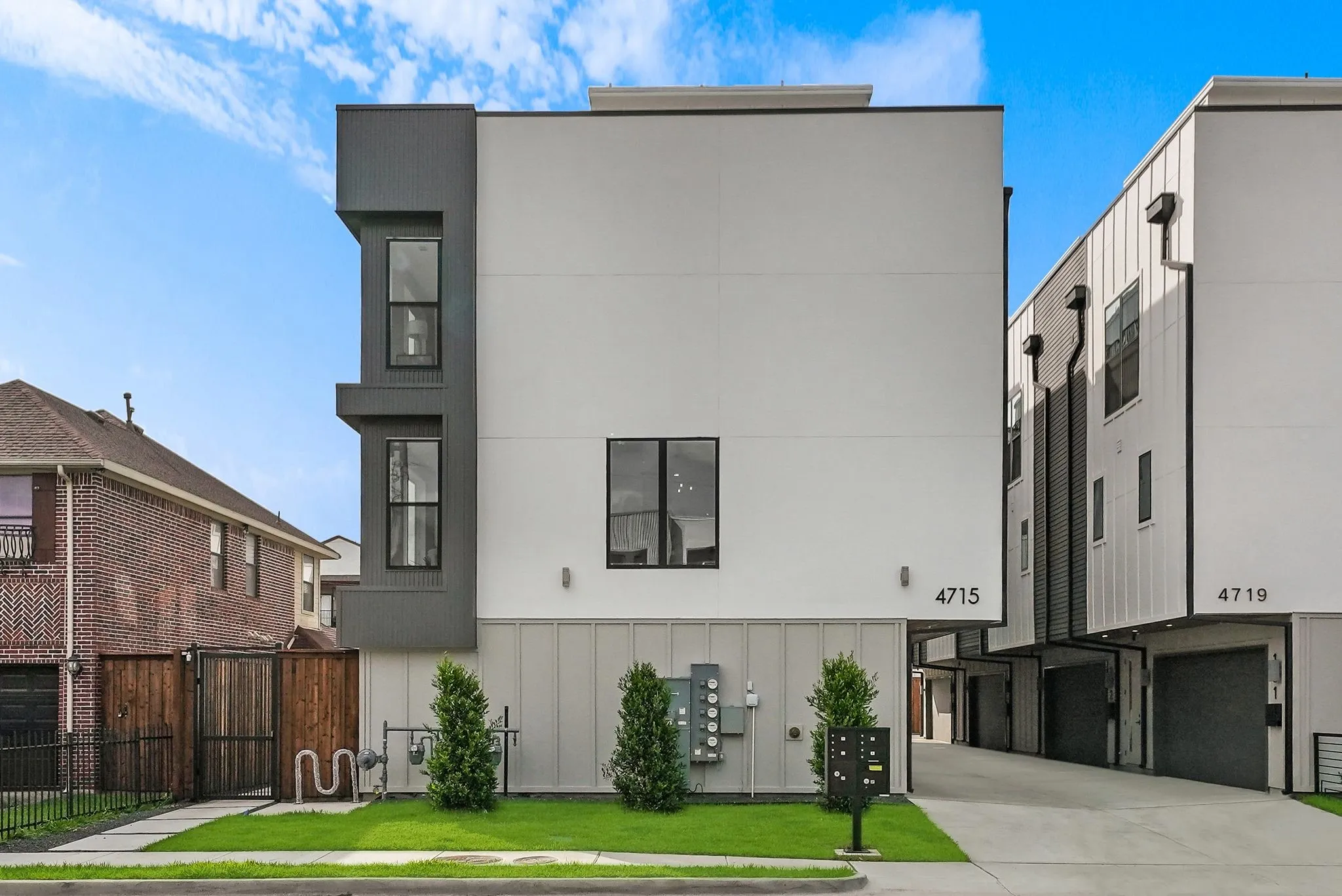 Modern multi-story facade featuring a white stucco finish with dark panel accents