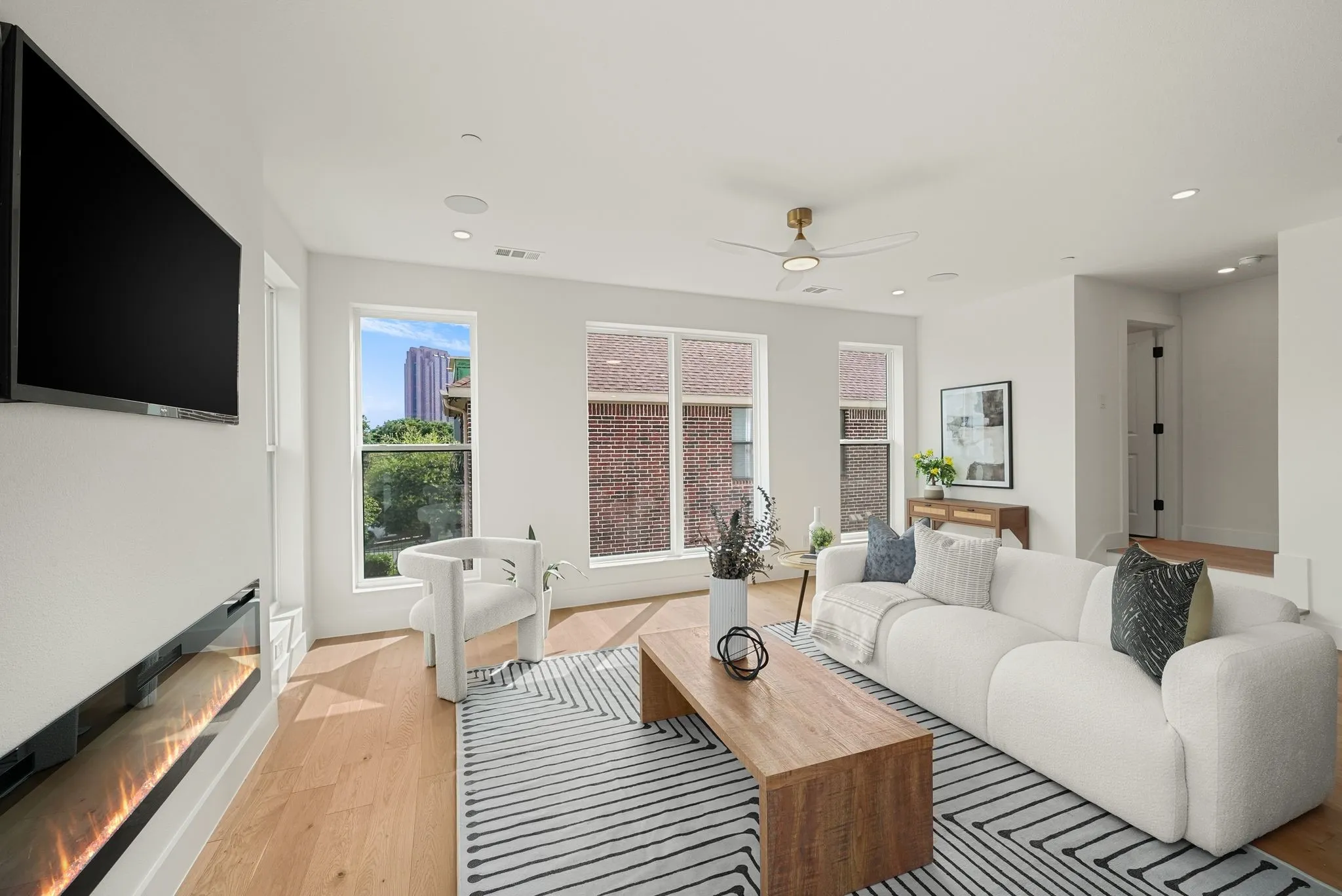 Spacious living area featuring light wood-finish flooring, recessed lighting, and large windows