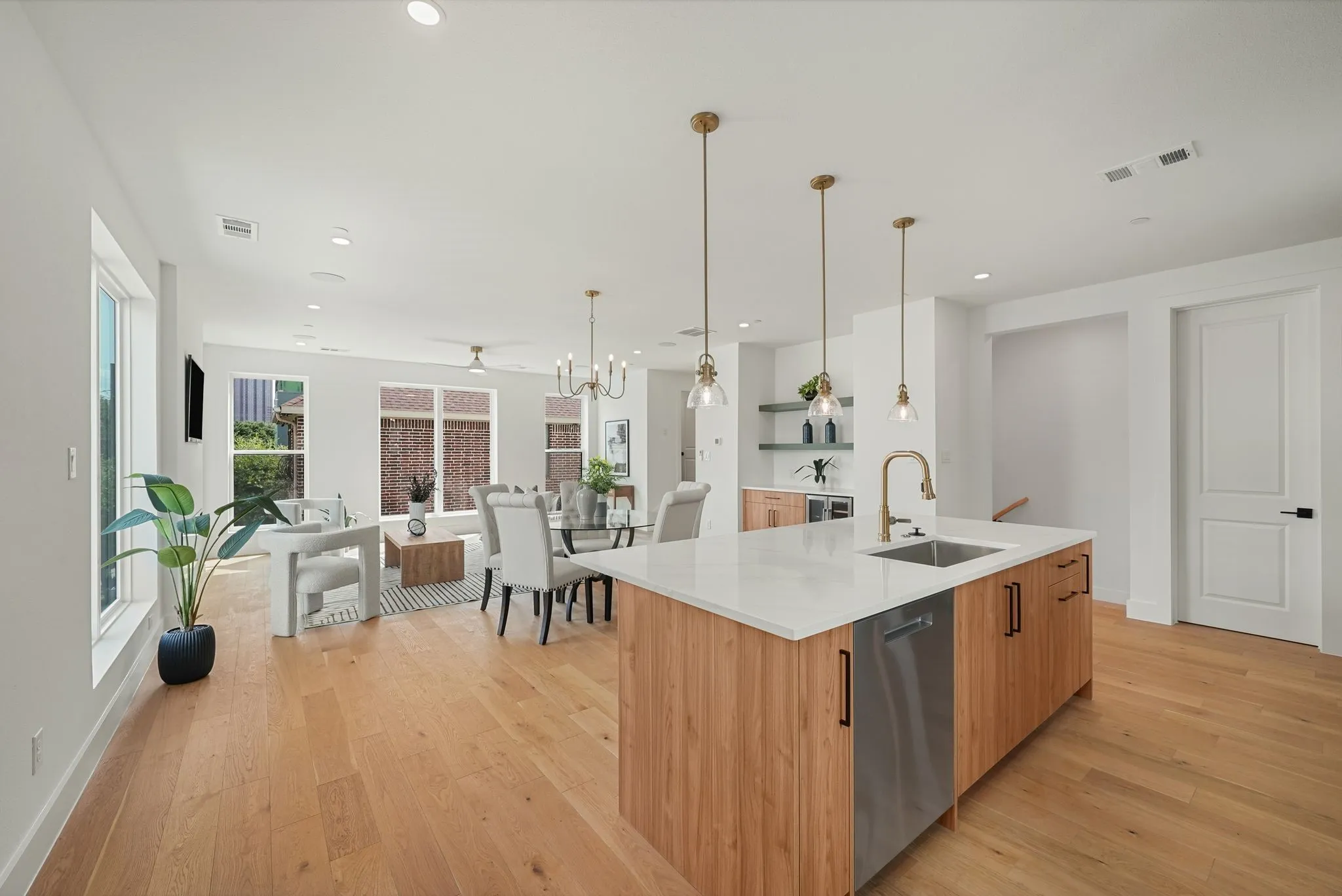 Open-concept living area featuring light wood-finish flooring, recessed lighting, and ample natural light from multiple windows