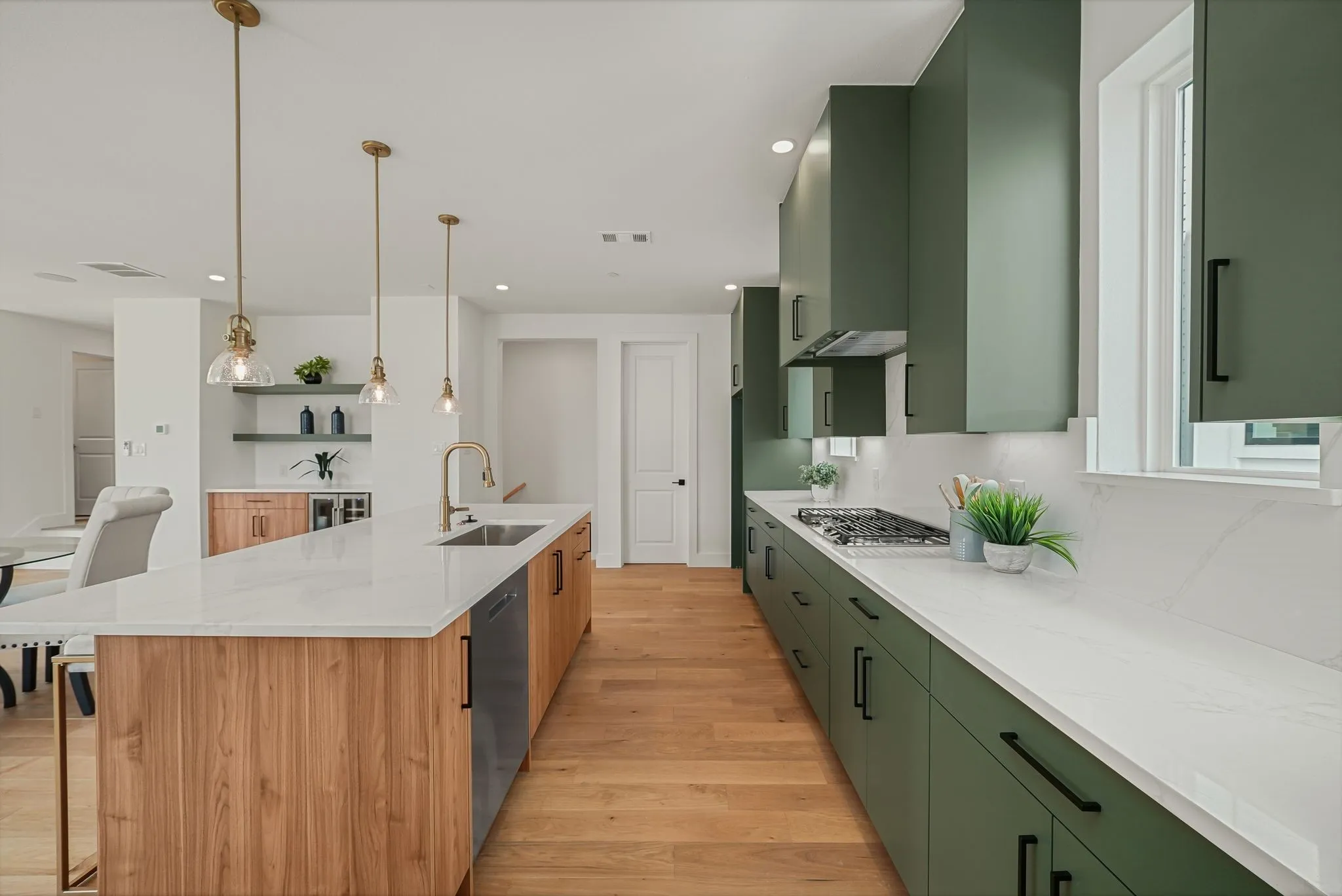 Modern kitchen featuring a spacious island with wood-finish paneling, white countertops, and integrated sink
