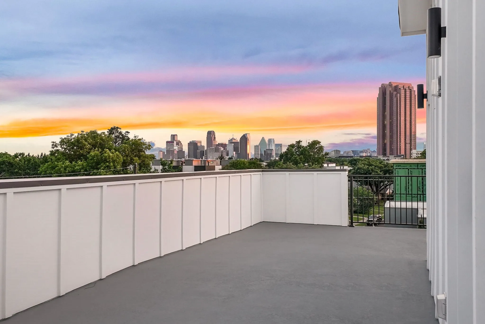 Rooftop deck featuring a cityscape backdrop, low-profile perimeter walls, and contemporary exterior lighting fixtures