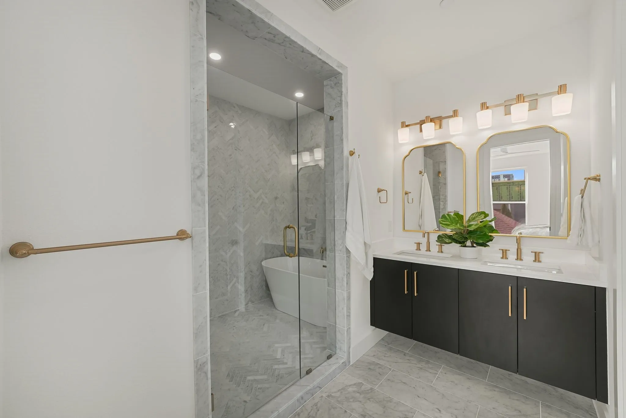 Modern bathroom featuring a double vanity with dark cabinetry and gold-tone hardware