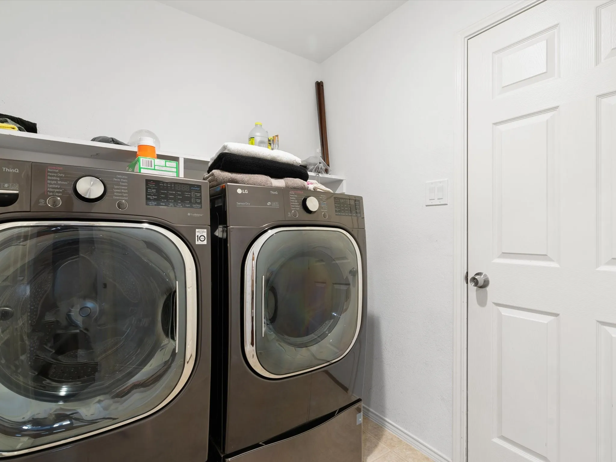 Laundry area featuring washer and dryer and light tile patterned floors