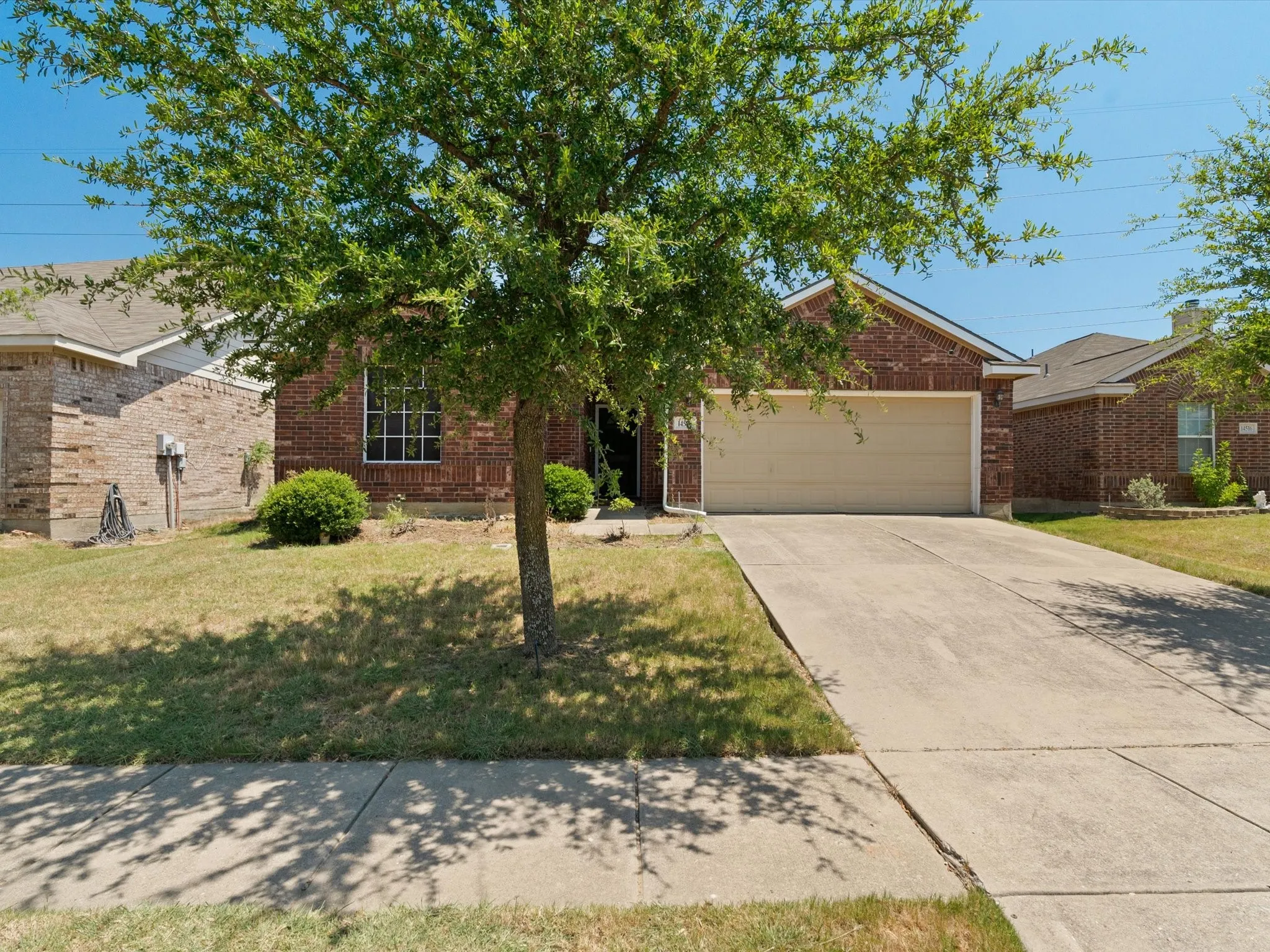View of property hidden behind natural elements with a garage and a front lawn