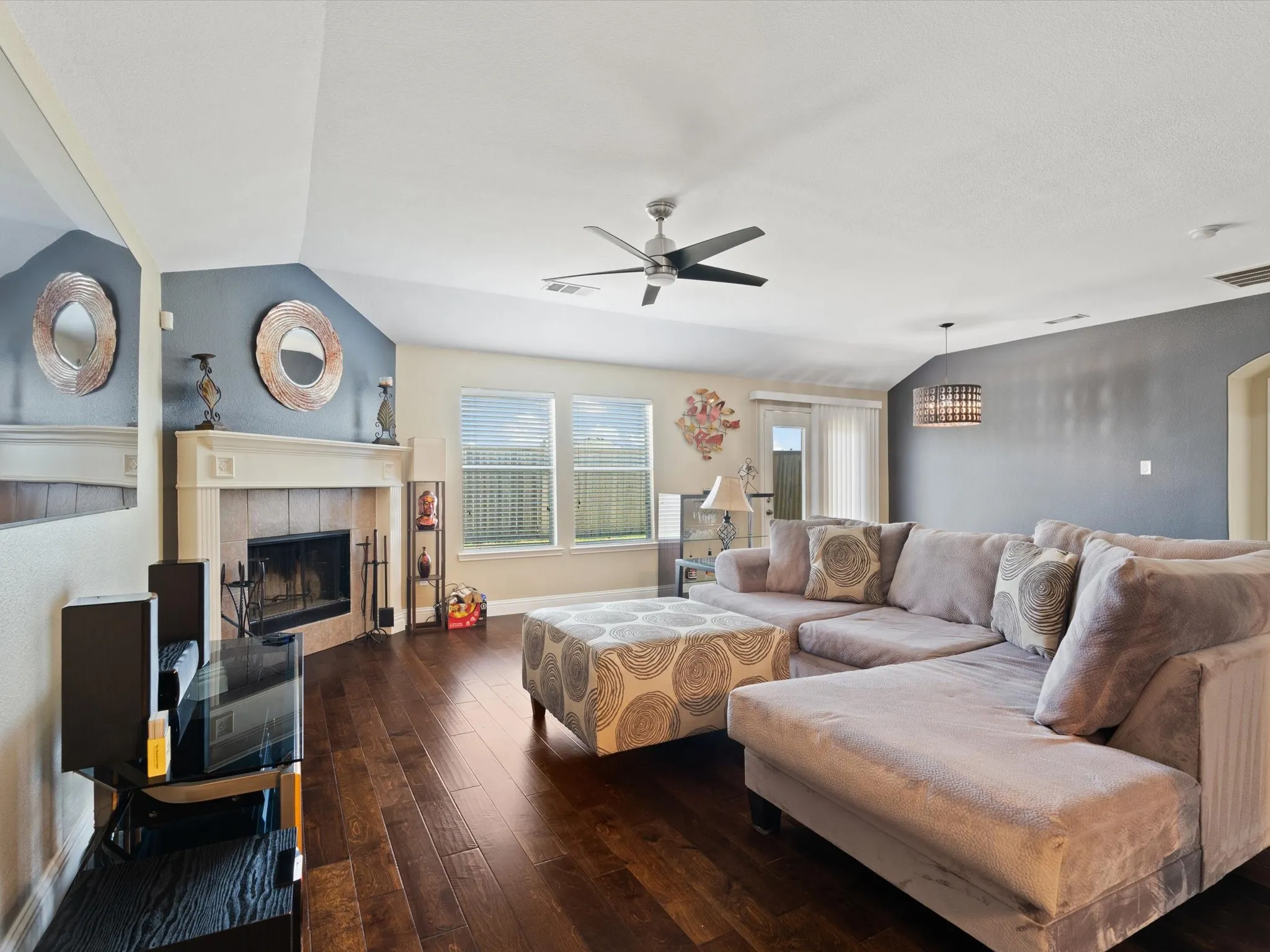 Living room with dark hardwood / wood-style floors, lofted ceiling, a tile fireplace, and ceiling fan