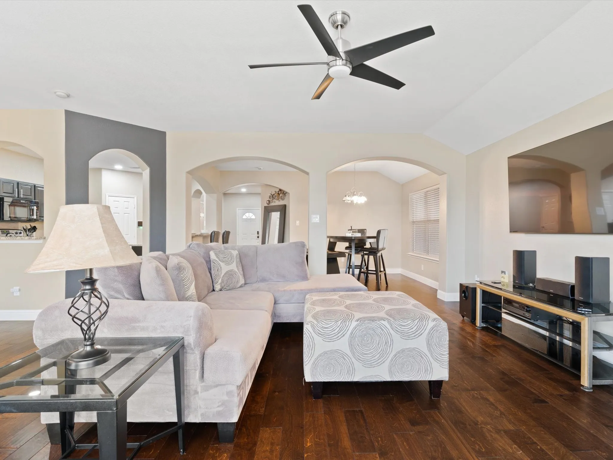 Living room with ceiling fan with notable chandelier, dark hardwood / wood-style flooring, and lofted ceiling
