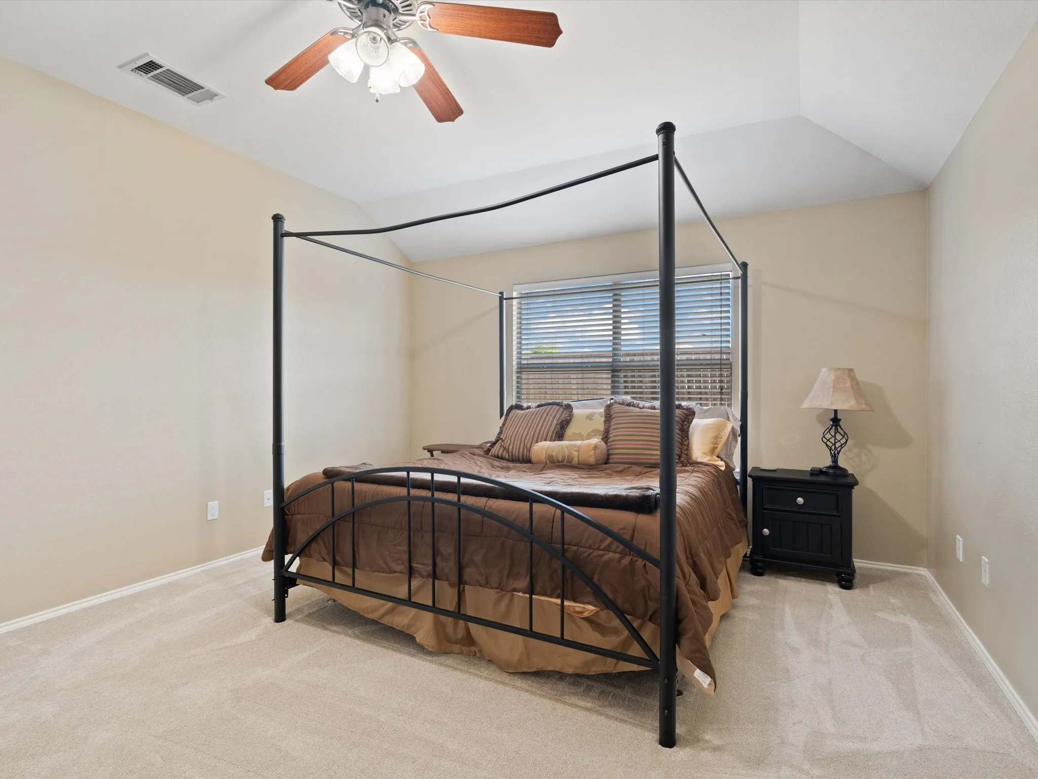 Bedroom featuring ceiling fan, vaulted ceiling, and light colored carpet