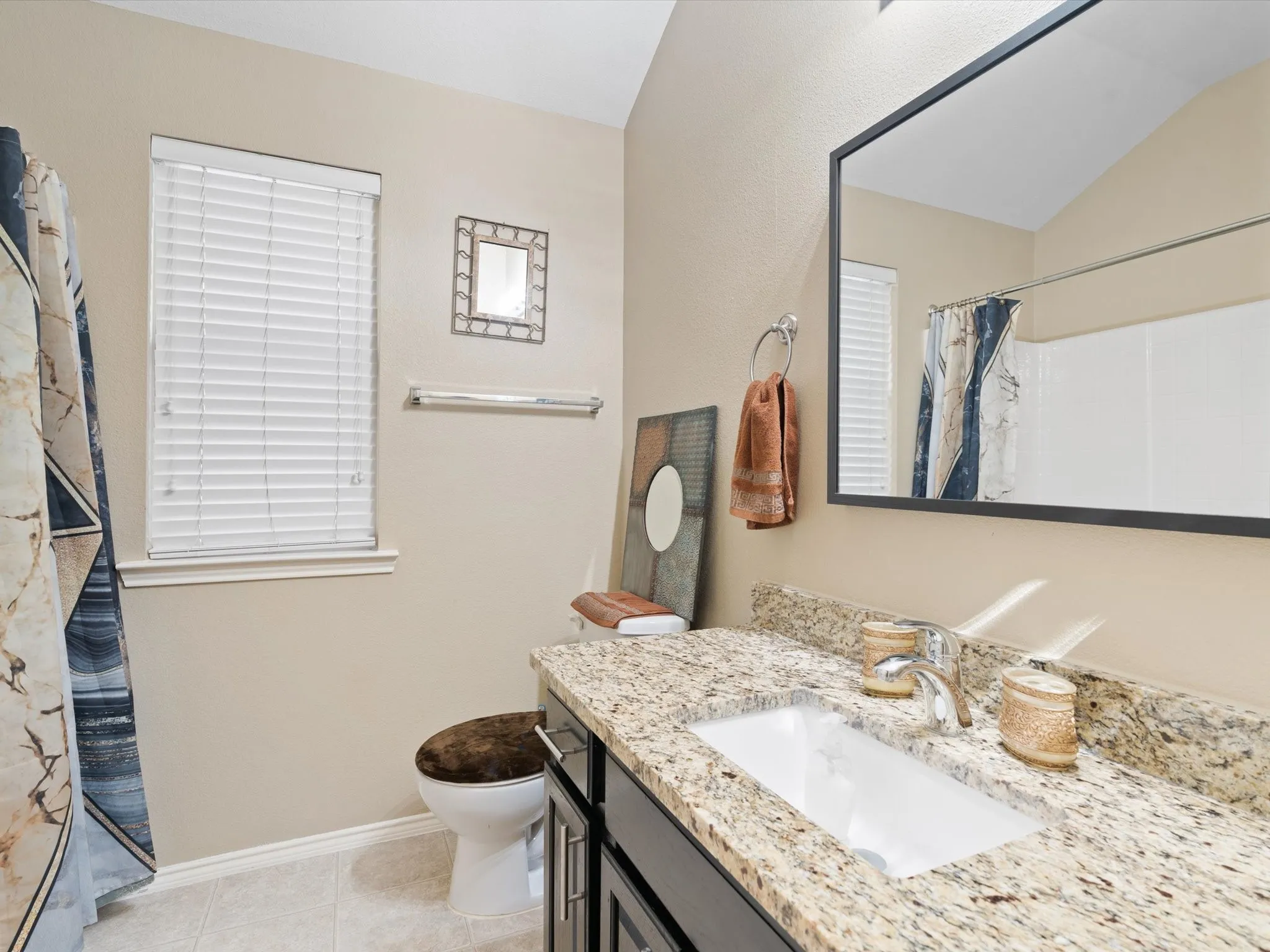 Bathroom featuring vaulted ceiling, vanity, tile patterned flooring, and toilet