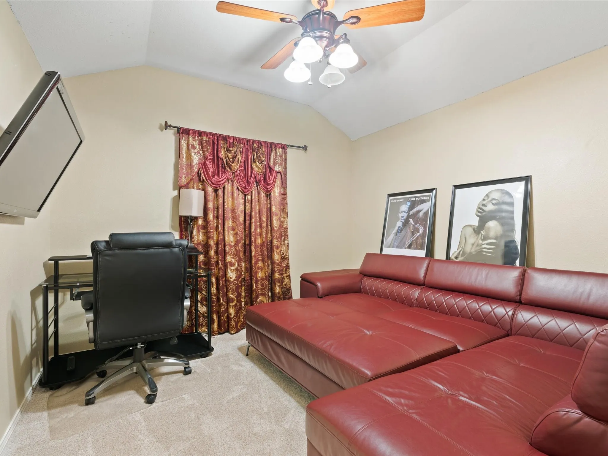 Carpeted office space with lofted ceiling and ceiling fan