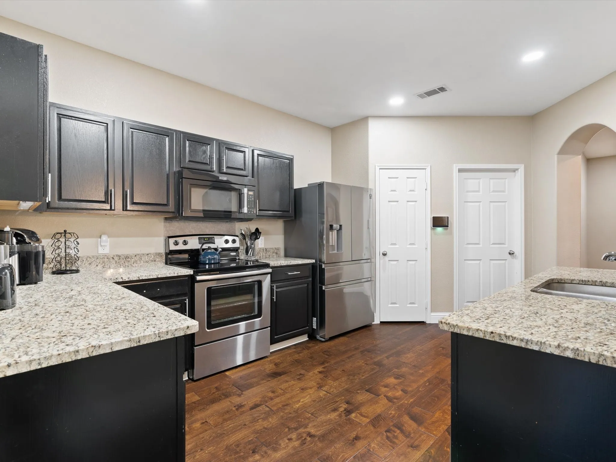 Kitchen featuring sink, dark hardwood / wood-style flooring, light stone counters, and stainless steel appliances
