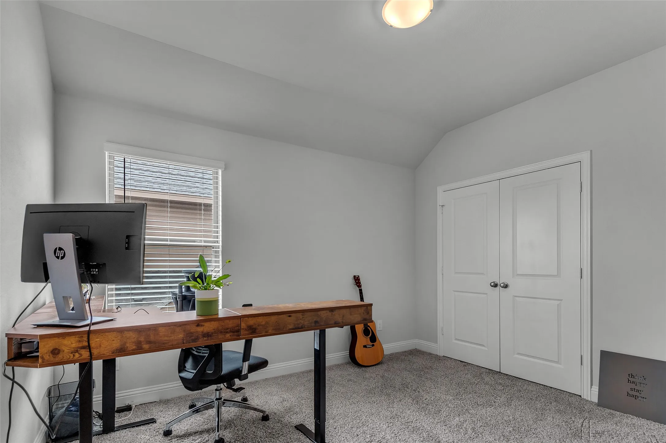 Office with lofted ceiling and light colored carpet
