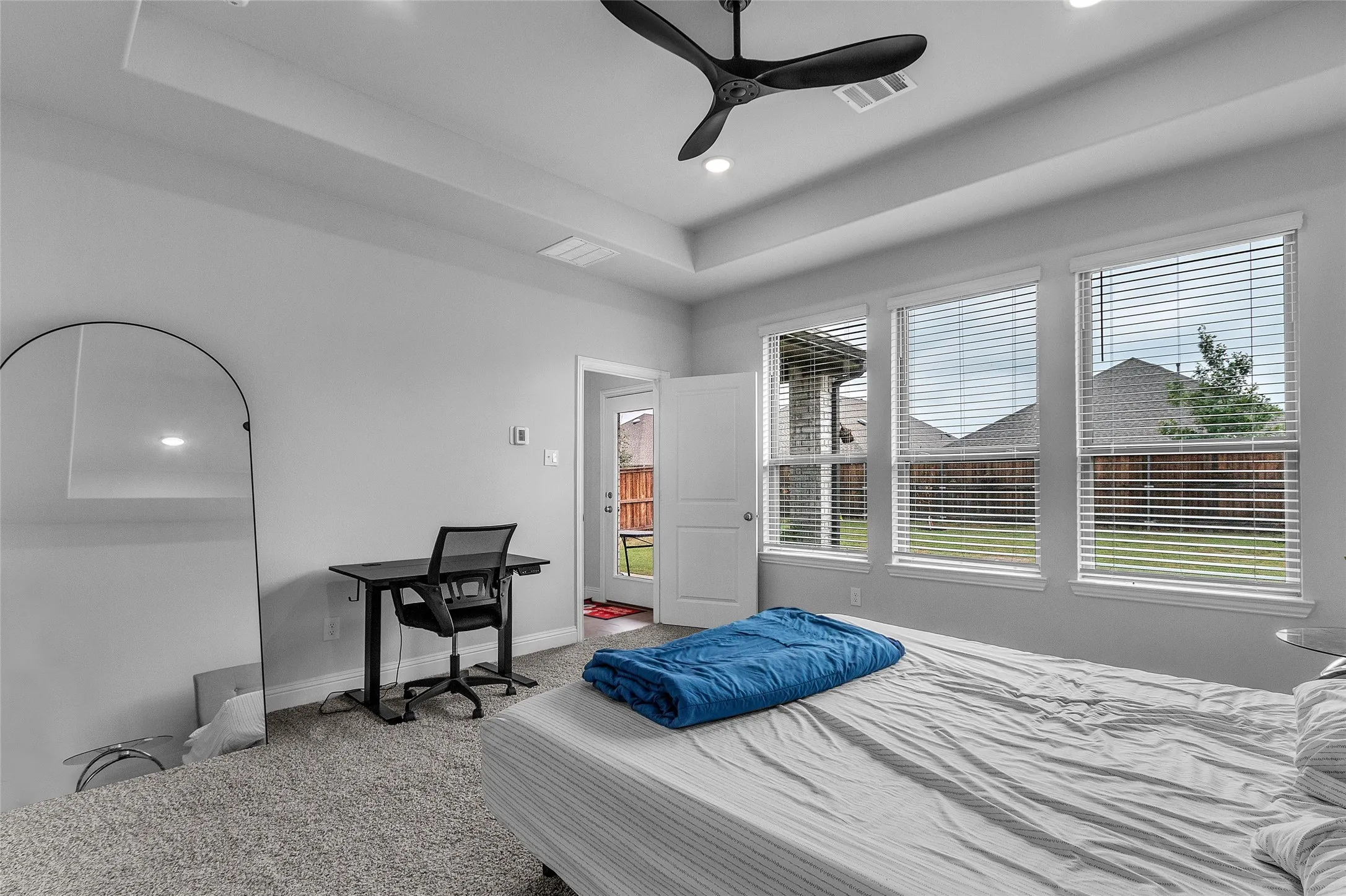 Bedroom with multiple windows, a tray ceiling, and ceiling fan