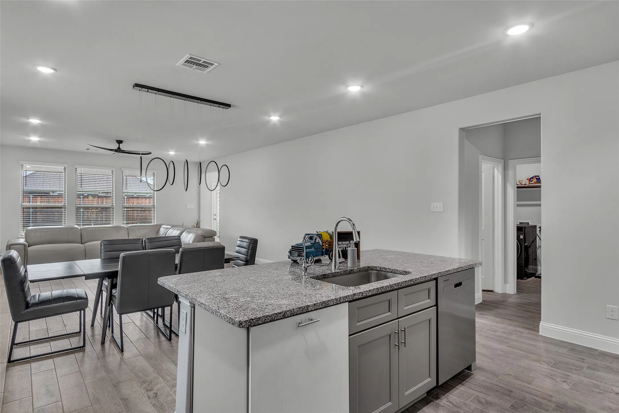 Kitchen featuring light hardwood / wood-style flooring, an island with sink, stainless steel dishwasher, sink, and light stone counters