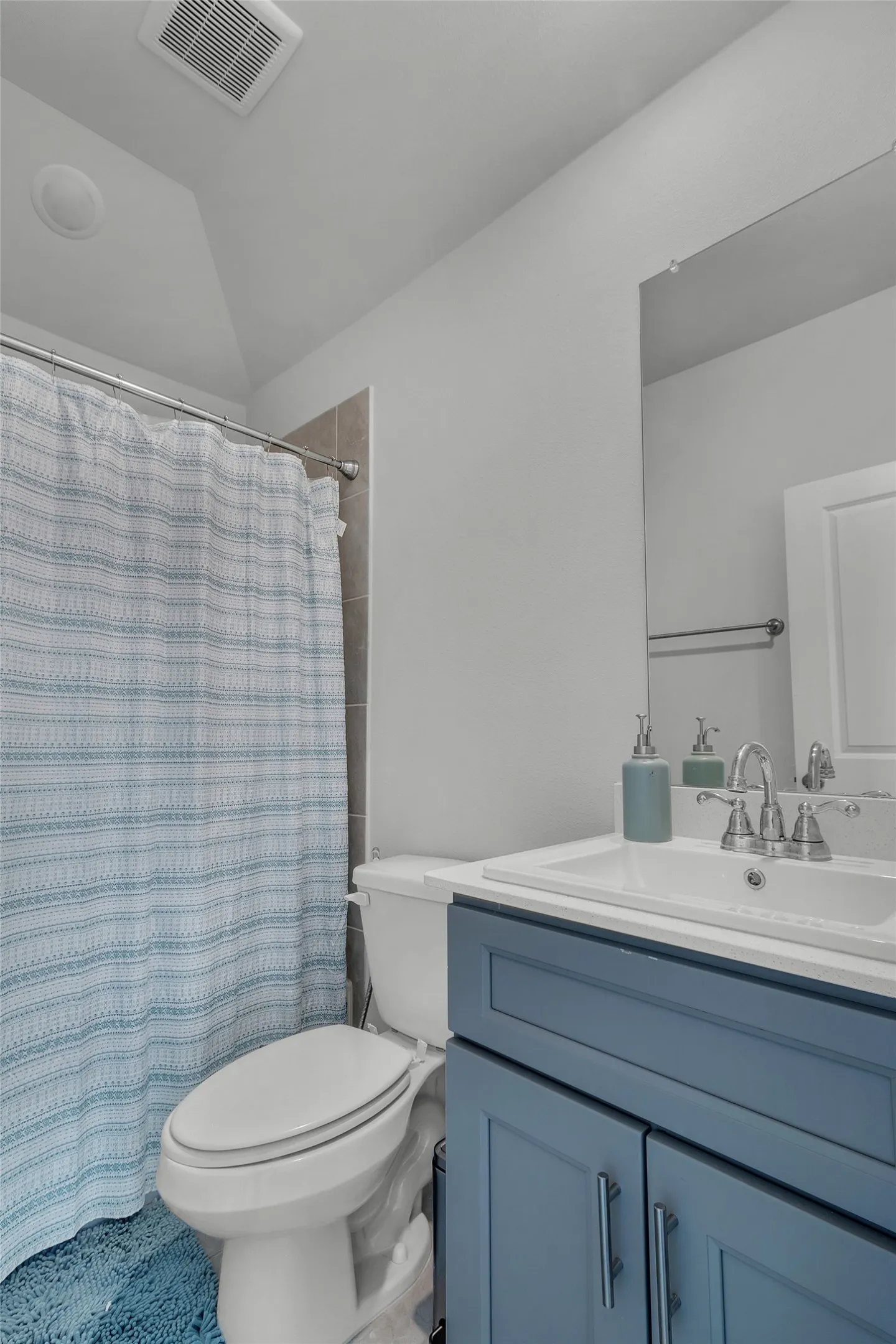 Bathroom featuring vanity, toilet, curtained shower, and vaulted ceiling