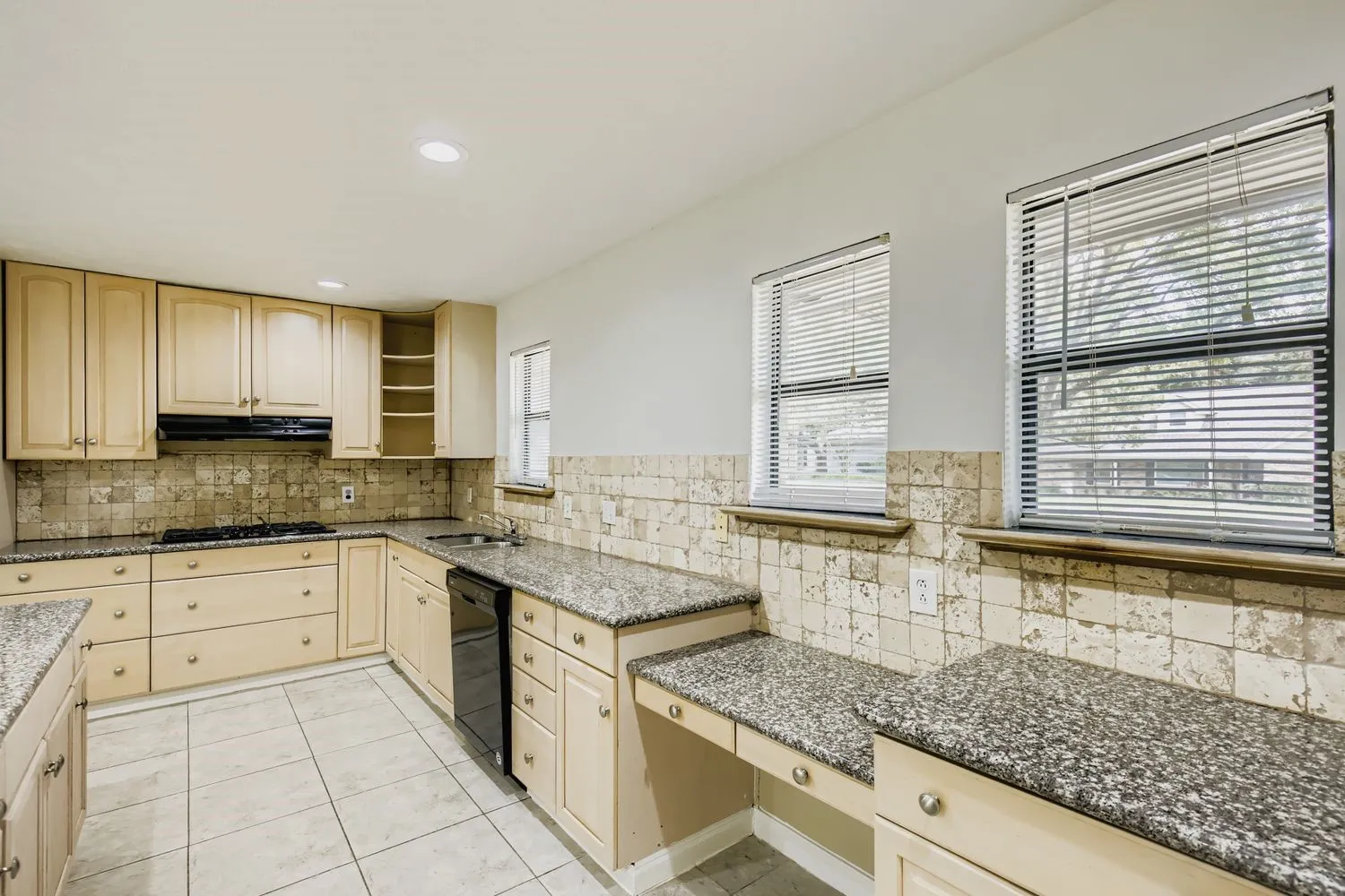 Kitchen featuring wood-finish cabinetry, granite-style countertops, black appliances, and tile flooring