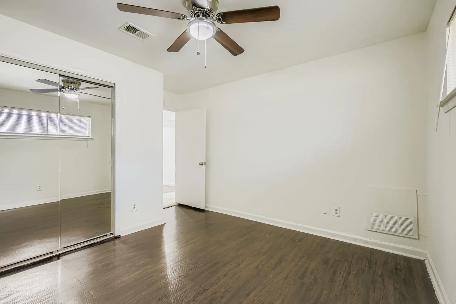 Room featuring dark wood-finish flooring, white walls, and a ceiling fan with light fixture