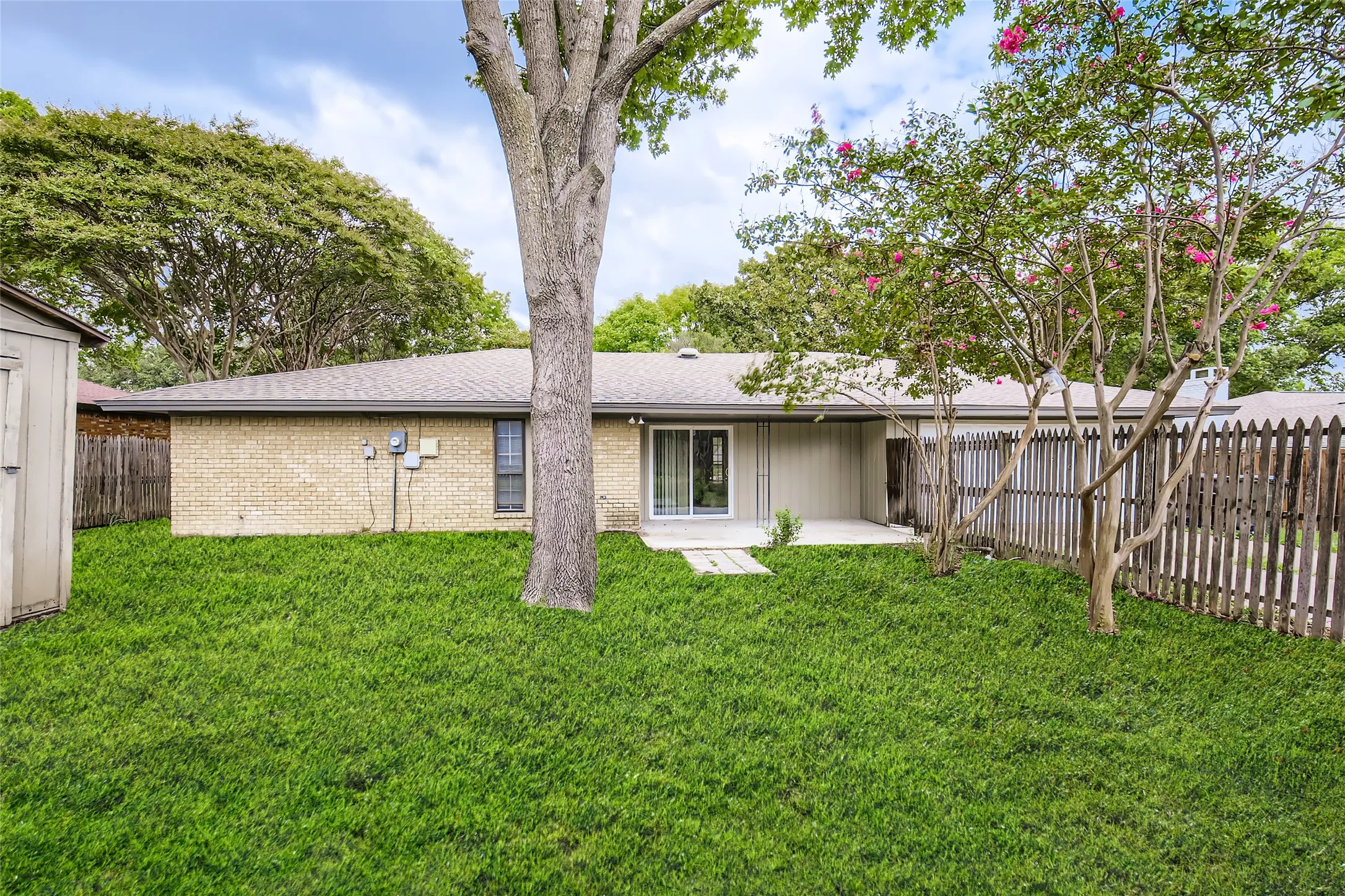 Expansive green lawn featuring mature trees and flowering bushes