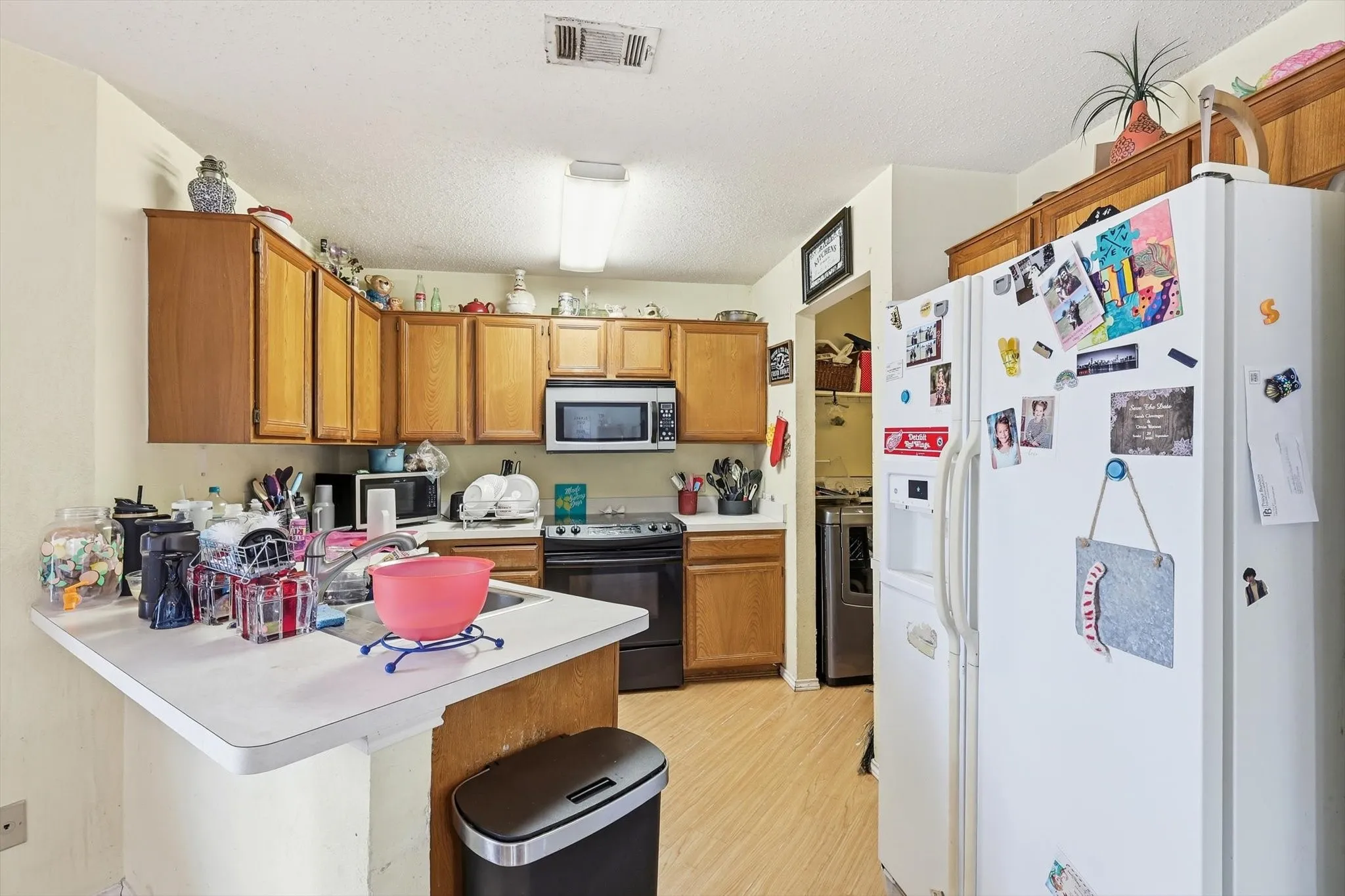 Kitchen featuring wood-finish cabinetry, white countertops, and a stainless steel sink