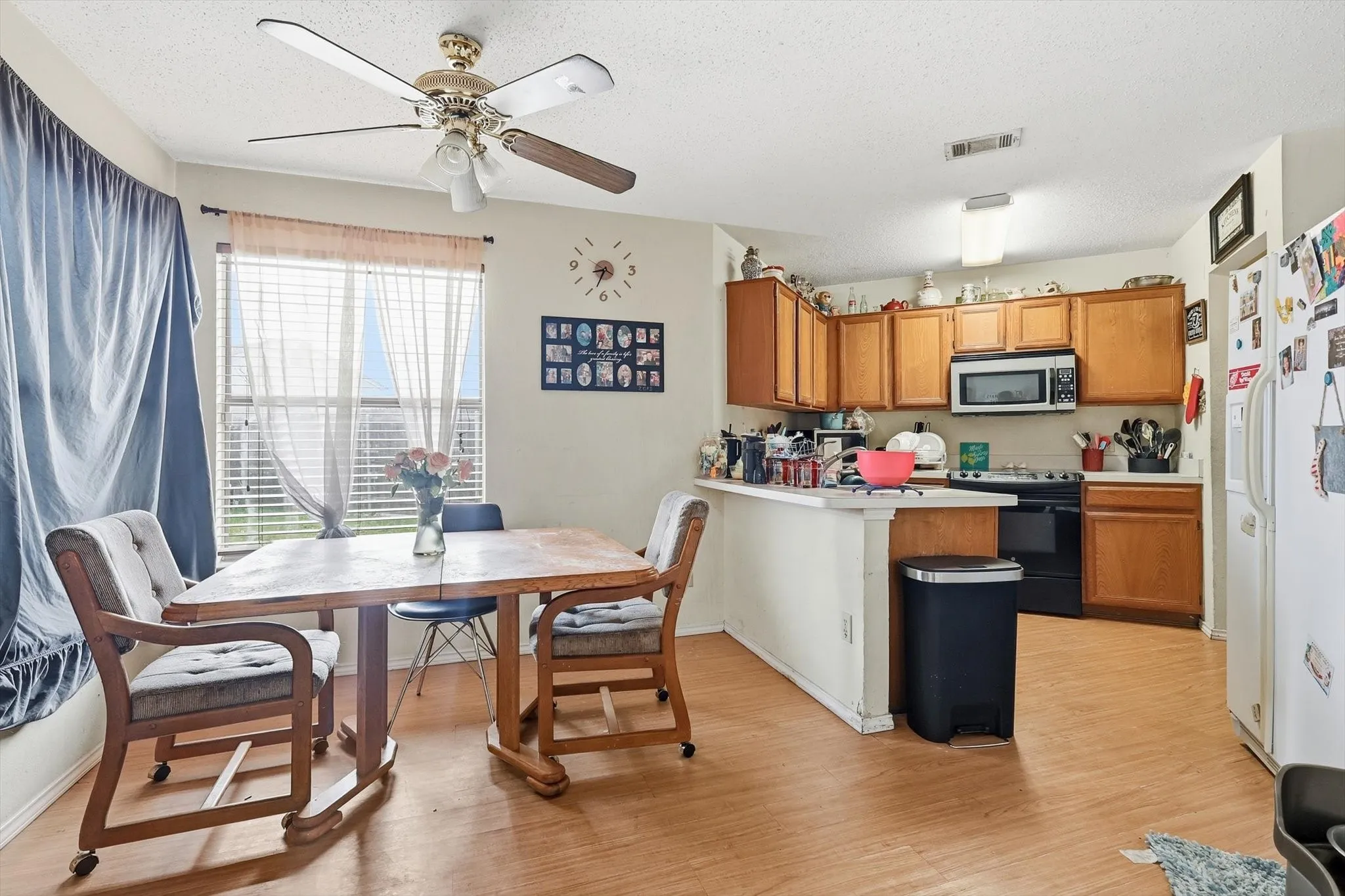 Dining area next to kitchen with ceiling fan and wood-look flooring