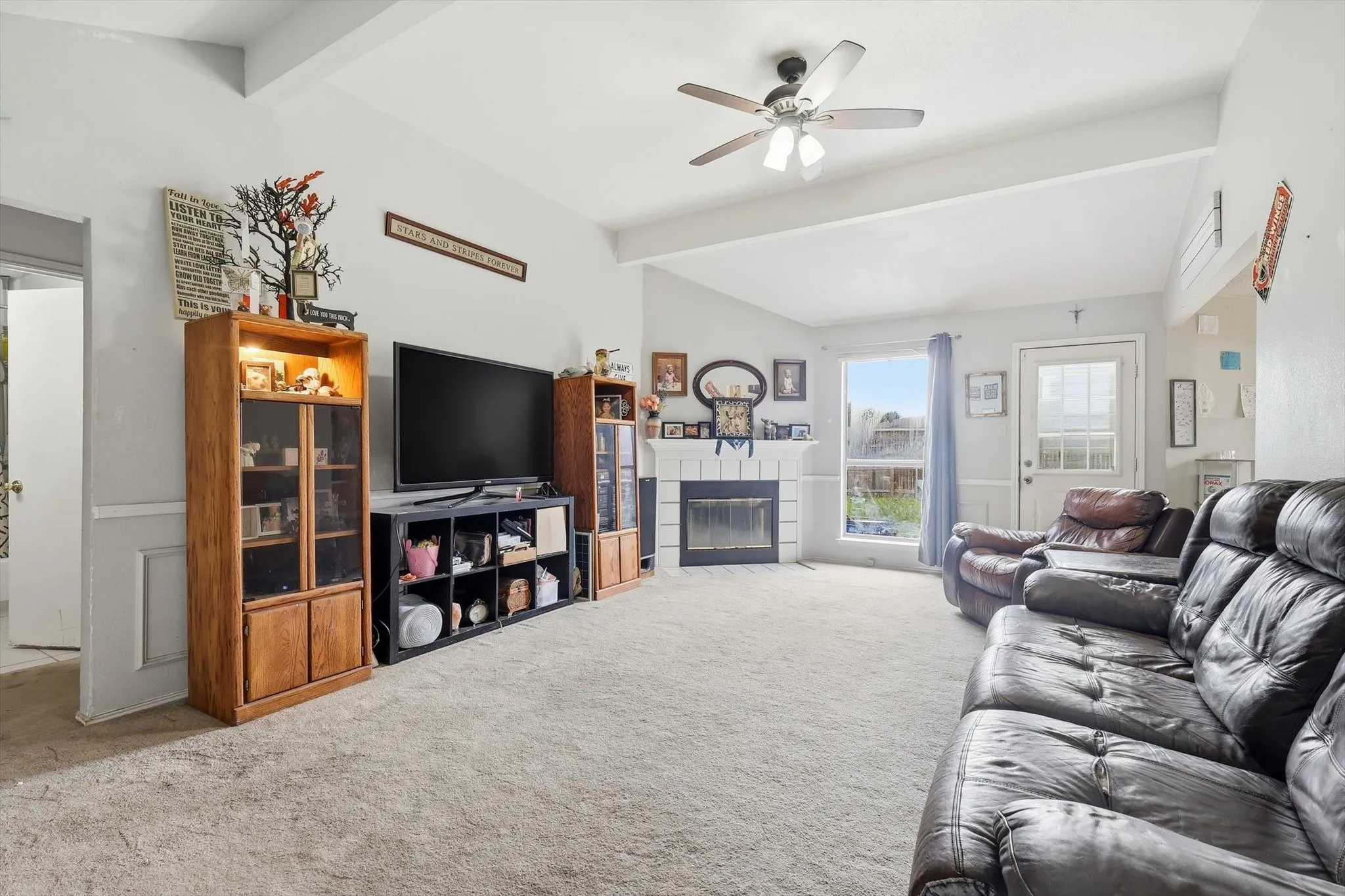 Spacious living area featuring vaulted ceilings, a ceiling fan, fireplace, and light-colored carpeting