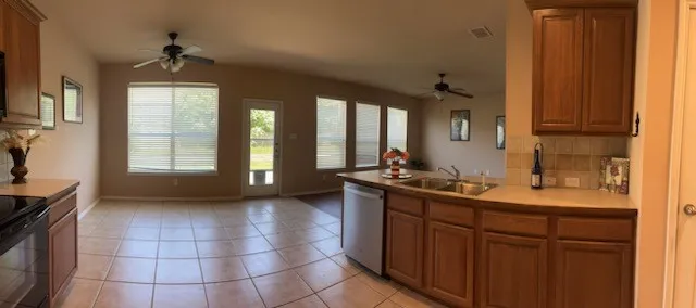 Kitchen with ceiling fan, tasteful backsplash, stainless steel dishwasher, and light tile floors