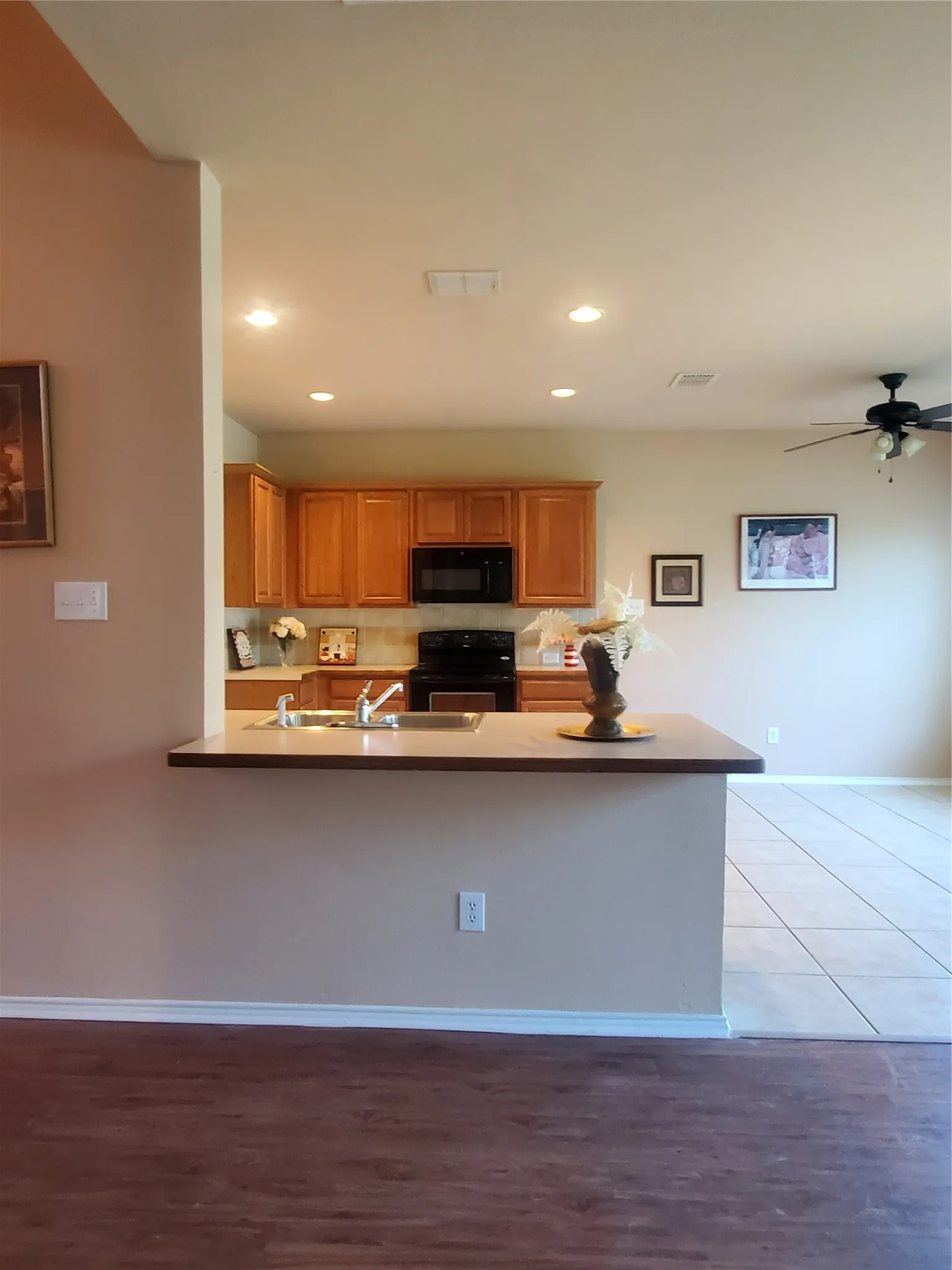 Kitchen featuring light hardwood / wood-style floors, kitchen peninsula, stove, ceiling fan, and sink