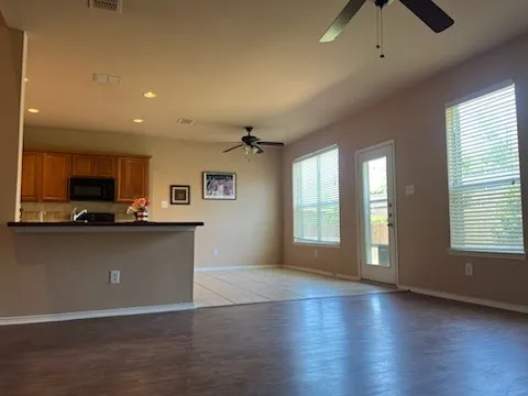 Living room with laminate flooring, ceiling fan, open to neighboring kitchen